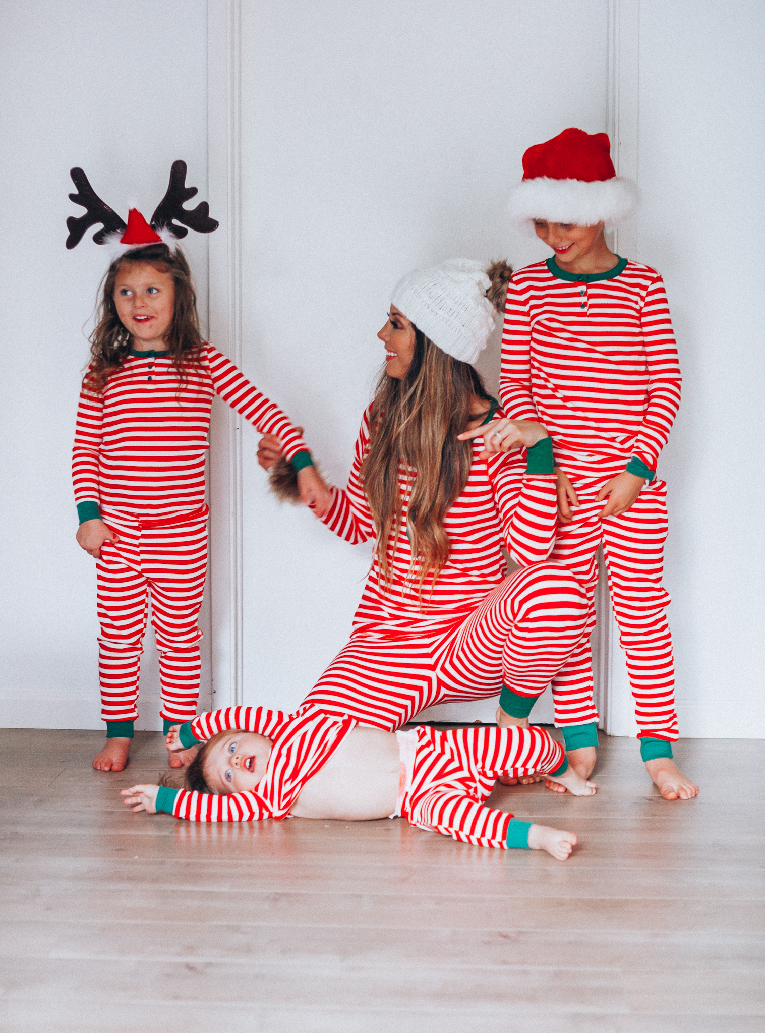 The Best Family Christmas Pajamas by popular San Francisco life and style blog, The Girl in the Yellow Dress: image of a mom and her kids standing together and wearing Old Navy Micro Performance Fleece Pajama Set for Women, Amazon Elowel Boys Girls Christmas Striped 2 Piece Kids Pajamas Set, and J. Crew Ribbed beanie with faux-fur pom-pom.