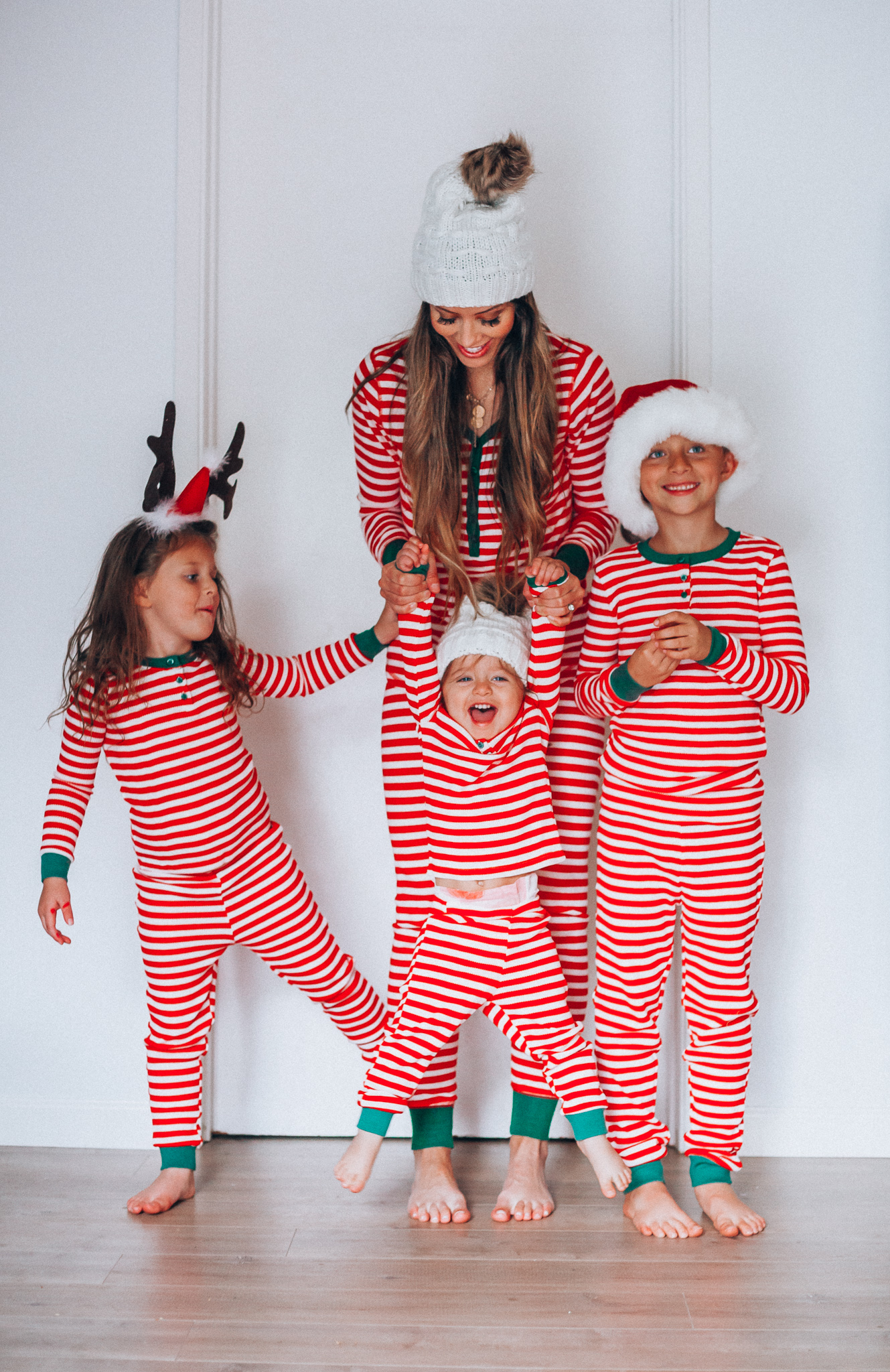 The Best Family Christmas Pajamas by popular San Francisco life and style blog, The Girl in the Yellow Dress: image of a mom and her kids standing together and wearing Old Navy Micro Performance Fleece Pajama Set for Women, Amazon Elowel Boys Girls Christmas Striped 2 Piece Kids Pajamas Set, and J. Crew Ribbed beanie with faux-fur pom-pom.