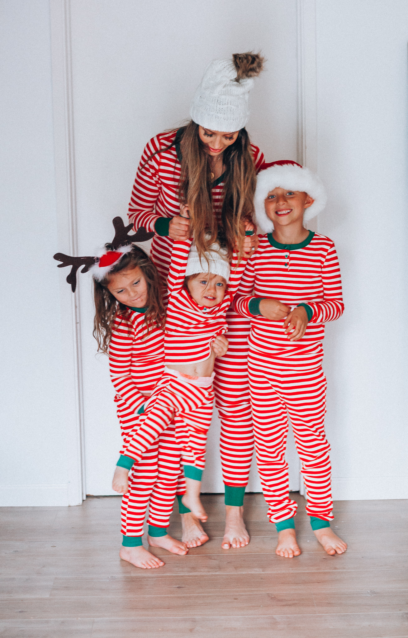 The Best Family Christmas Pajamas by popular San Francisco life and style blog, The Girl in the Yellow Dress: image of a mom and her kids standing together and wearing Old Navy Micro Performance Fleece Pajama Set for Women, Amazon Elowel Boys Girls Christmas Striped 2 Piece Kids Pajamas Set, and J. Crew Ribbed beanie with faux-fur pom-pom.