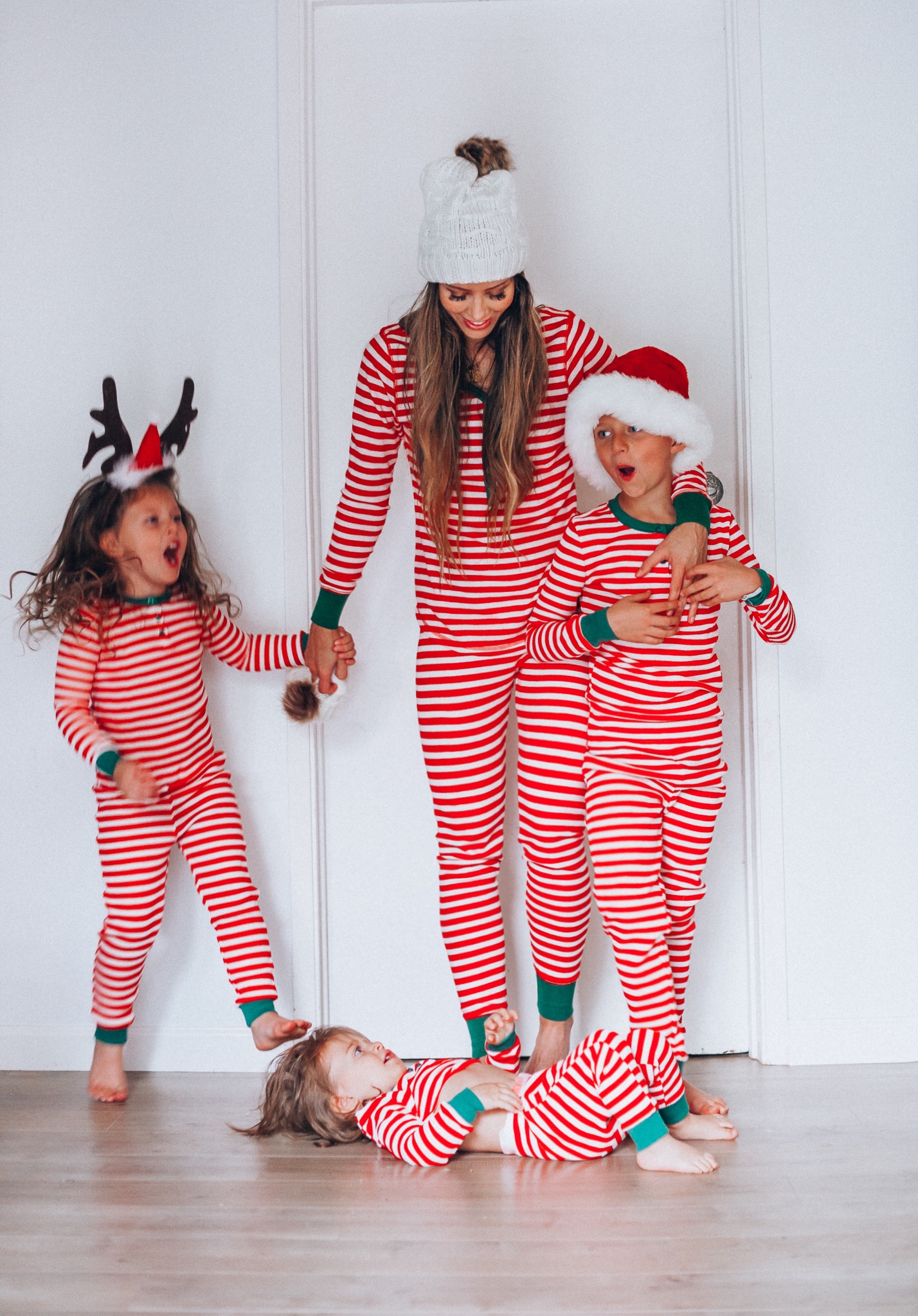 The Best Family Christmas Pajamas by popular San Francisco life and style blog, The Girl in the Yellow Dress: image of a mom and her kids standing together and wearing Old Navy Micro Performance Fleece Pajama Set for Women, Amazon Elowel Boys Girls Christmas Striped 2 Piece Kids Pajamas Set, and J. Crew Ribbed beanie with faux-fur pom-pom.