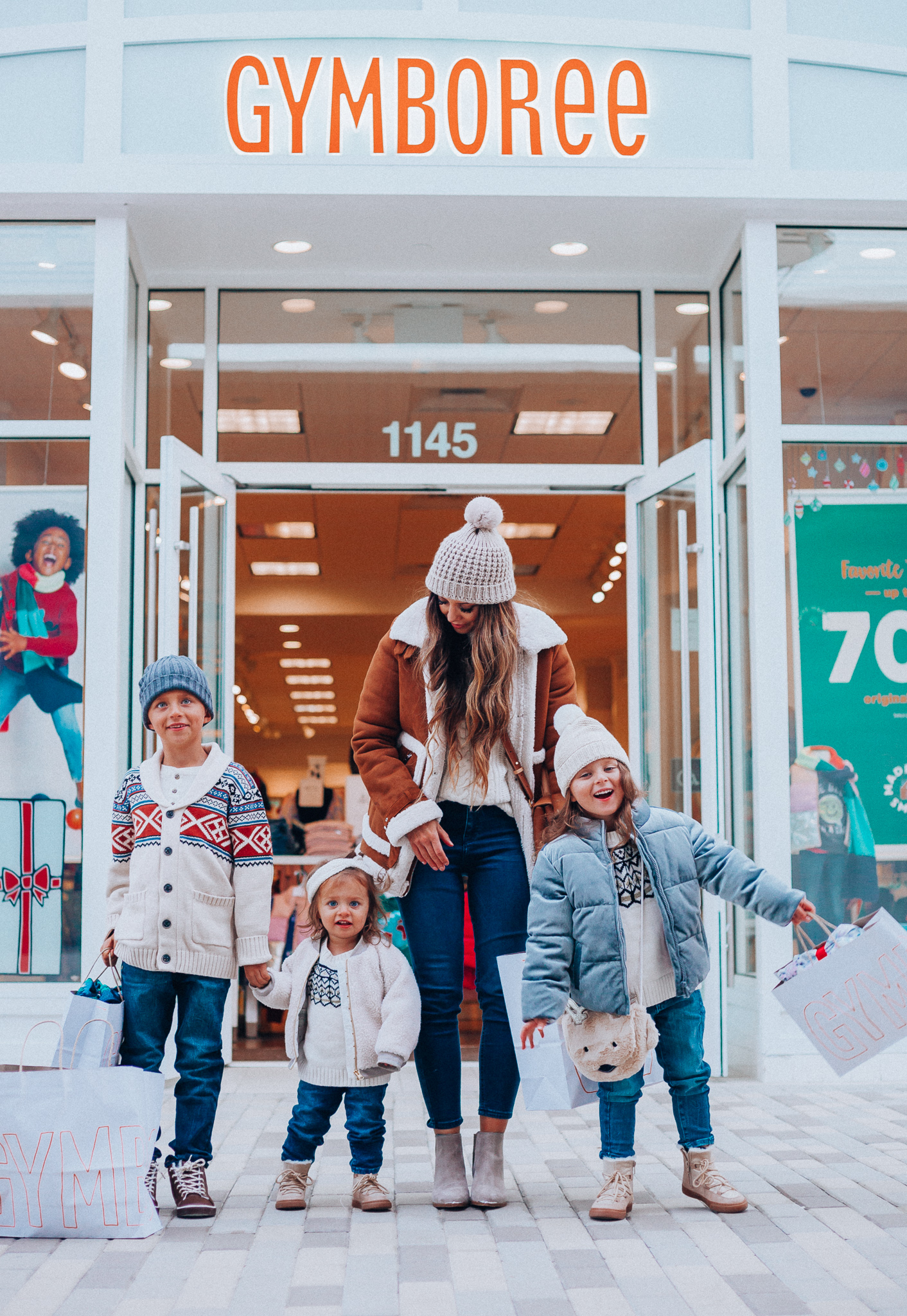 Gymboree Holiday Collection featured by top San Francisco fashion blog, The Girl in the Yellow Dress: image of a mom wearing a Abercrombie & Fitch mock neck sweater, high waist ankle jeans, Mark Fisher Chelsea boots, a pom pom beanie and a leather shoulder bag. A toddler wearing a Gymboree headband, sherpa jacket, sweater, jeggings and metallic moon boots. A boy wearing a Gymboree beanie, sweater, jeans and leather high tops. A girl wearing a Gymboree beanie, coat, sweater, jeans and boots