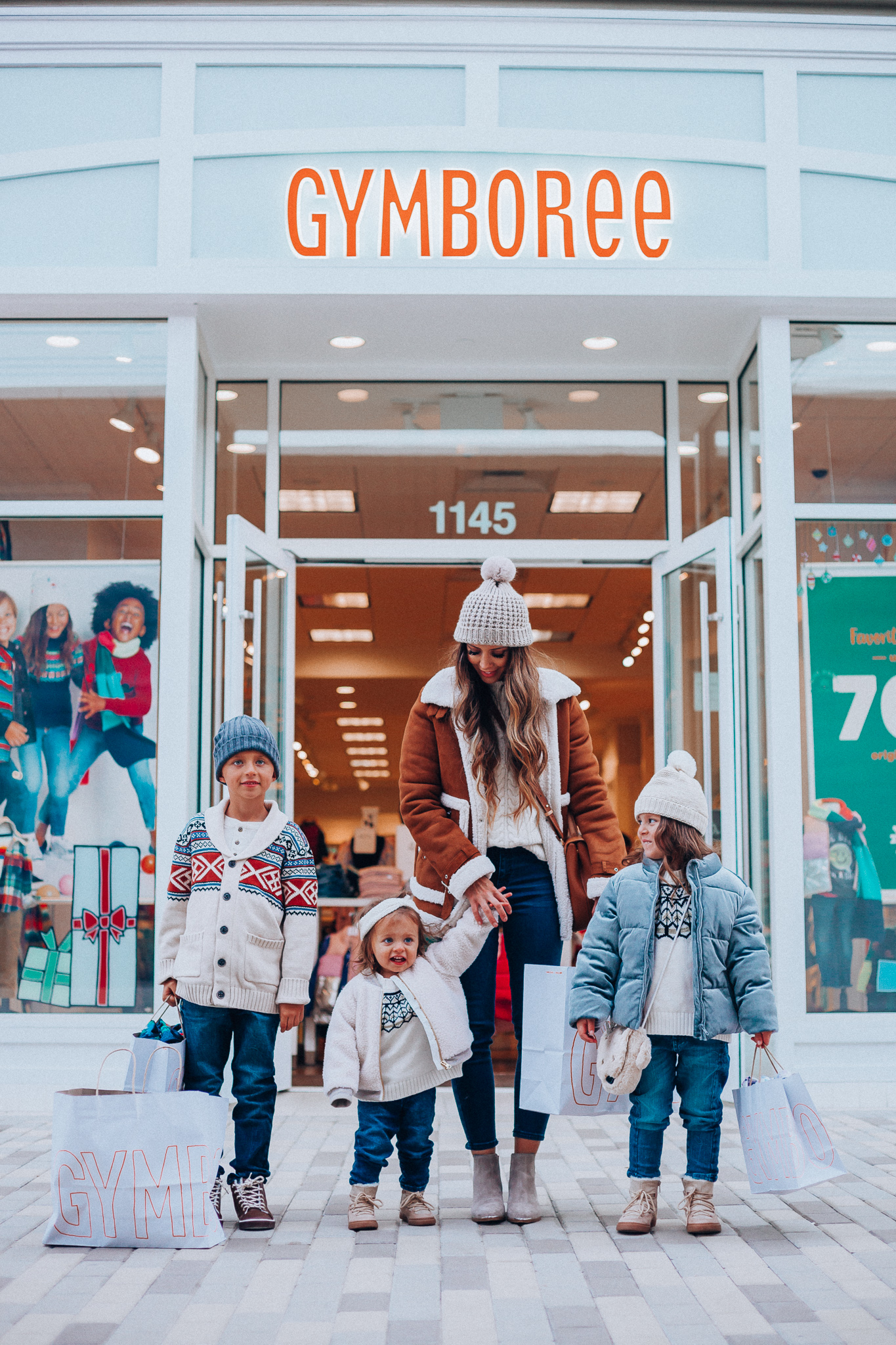 Gymboree Holiday Collection featured by top San Francisco fashion blog, The Girl in the Yellow Dress: image of a mom wearing a Abercrombie & Fitch mock neck sweater, high waist ankle jeans, Mark Fisher Chelsea boots, a pom pom beanie and a leather shoulder bag. A toddler wearing a Gymboree headband, sherpa jacket, sweater, jeggings and metallic moon boots. A boy wearing a Gymboree beanie, sweater, jeans and leather high tops. A girl wearing a Gymboree beanie, coat, sweater, jeans and boots