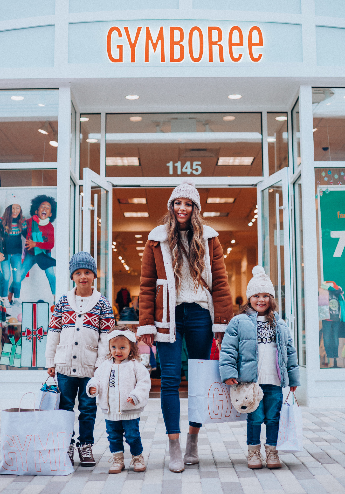 Gymboree Holiday Collection featured by top San Francisco fashion blog, The Girl in the Yellow Dress: image of a mom wearing a Abercrombie & Fitch mock neck sweater, high waist ankle jeans, Mark Fisher Chelsea boots, a pom pom beanie and a leather shoulder bag. A toddler wearing a Gymboree headband, sherpa jacket, sweater, jeggings and metallic moon boots. A boy wearing a Gymboree beanie, sweater, jeans and leather high tops. A girl wearing a Gymboree beanie, coat, sweater, jeans and boots