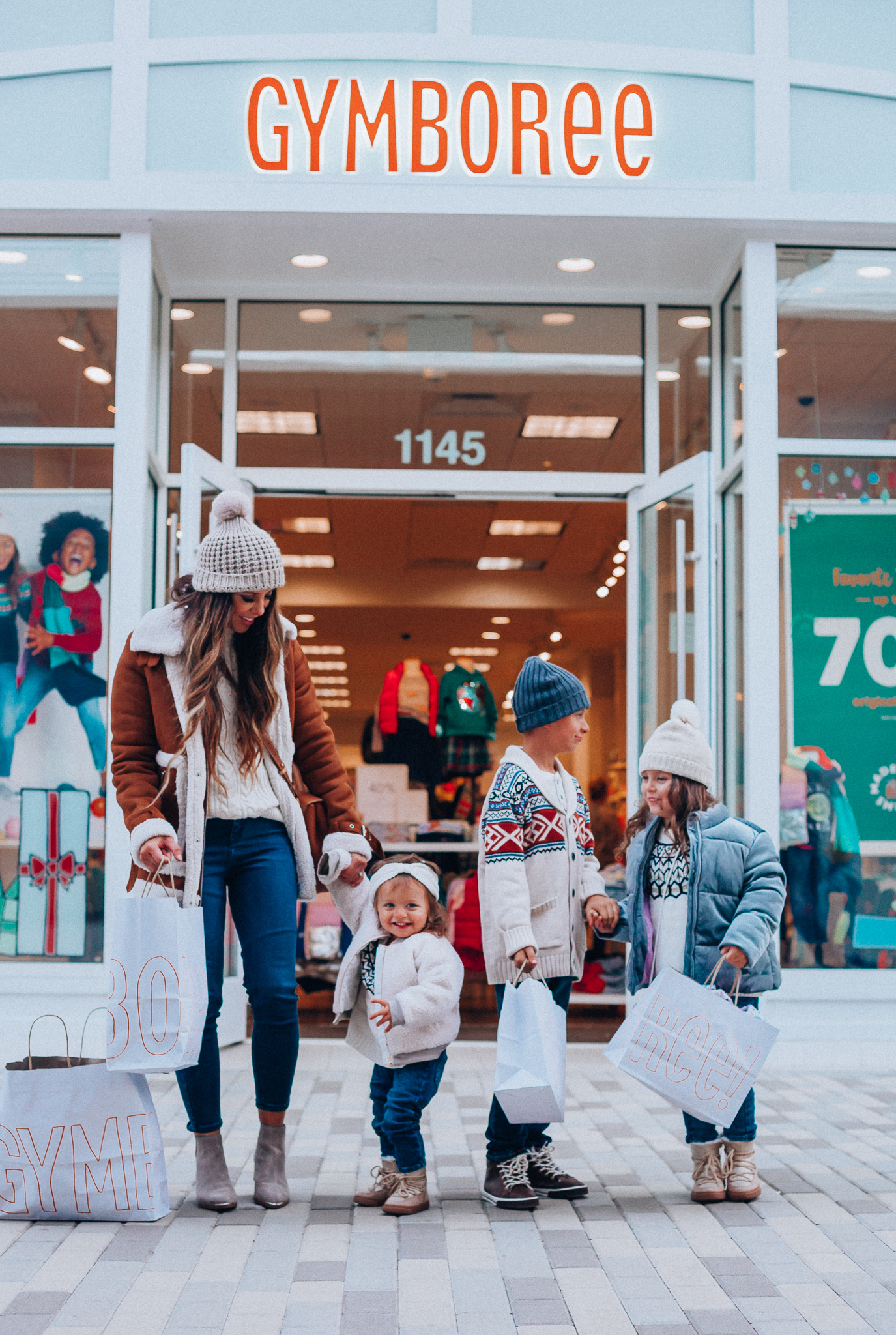 Gymboree Holiday Collection featured by top San Francisco fashion blog, The Girl in the Yellow Dress: image of a mom wearing a Abercrombie & Fitch mock neck sweater, high waist ankle jeans, Mark Fisher Chelsea boots, a pom pom beanie and a leather shoulder bag. A toddler wearing a Gymboree headband, sherpa jacket, sweater, jeggings and metallic moon boots. A boy wearing a Gymboree beanie, sweater, jeans and leather high tops. A girl wearing a Gymboree beanie, coat, sweater, jeans and boots