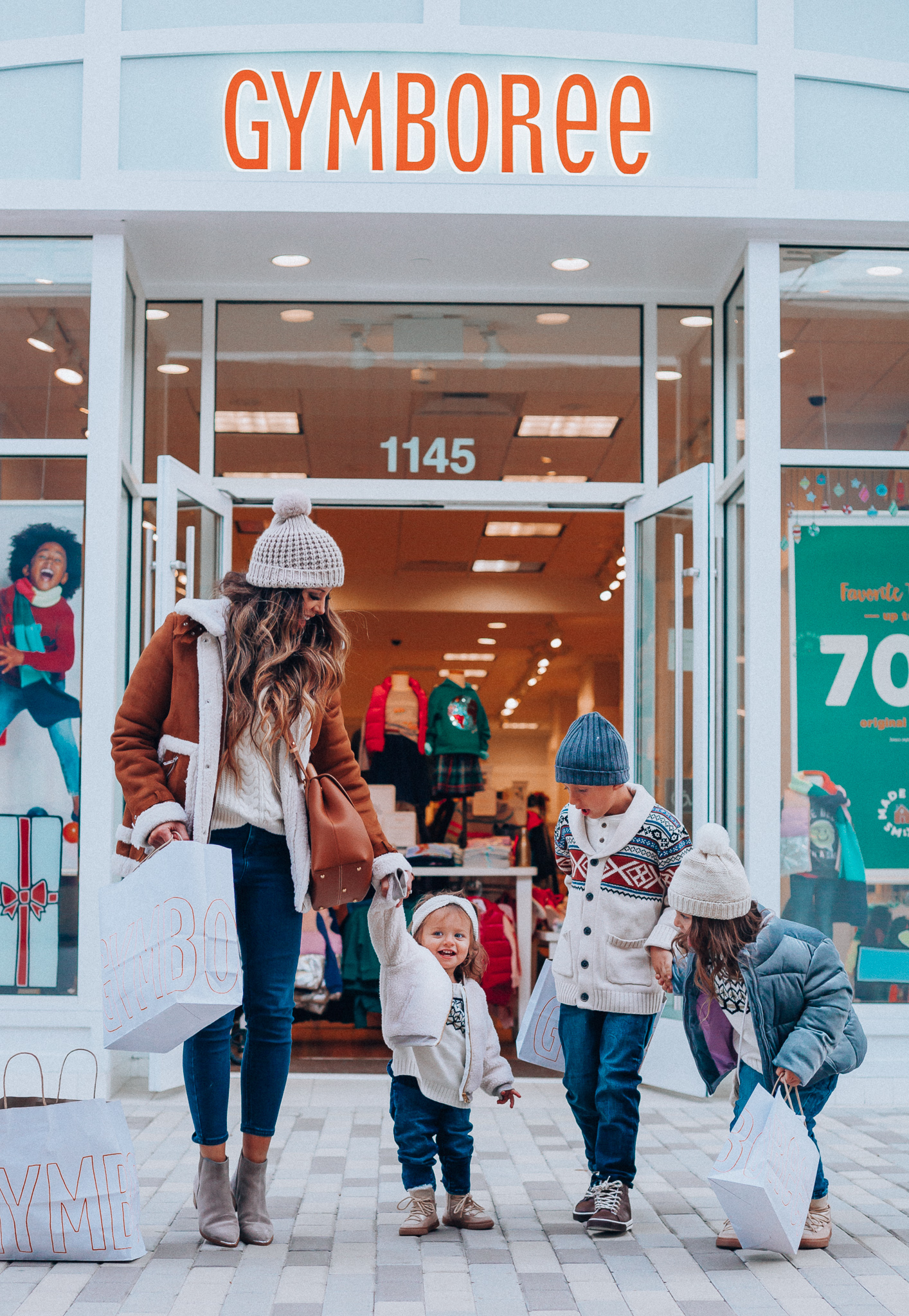 Gymboree Holiday Collection featured by top San Francisco fashion blog, The Girl in the Yellow Dress: image of a mom wearing a Abercrombie & Fitch mock neck sweater, high waist ankle jeans, Mark Fisher Chelsea boots, a pom pom beanie and a leather shoulder bag. A toddler wearing a Gymboree headband, sherpa jacket, sweater, jeggings and metallic moon boots. A boy wearing a Gymboree beanie, sweater, jeans and leather high tops. A girl wearing a Gymboree beanie, coat, sweater, jeans and boots