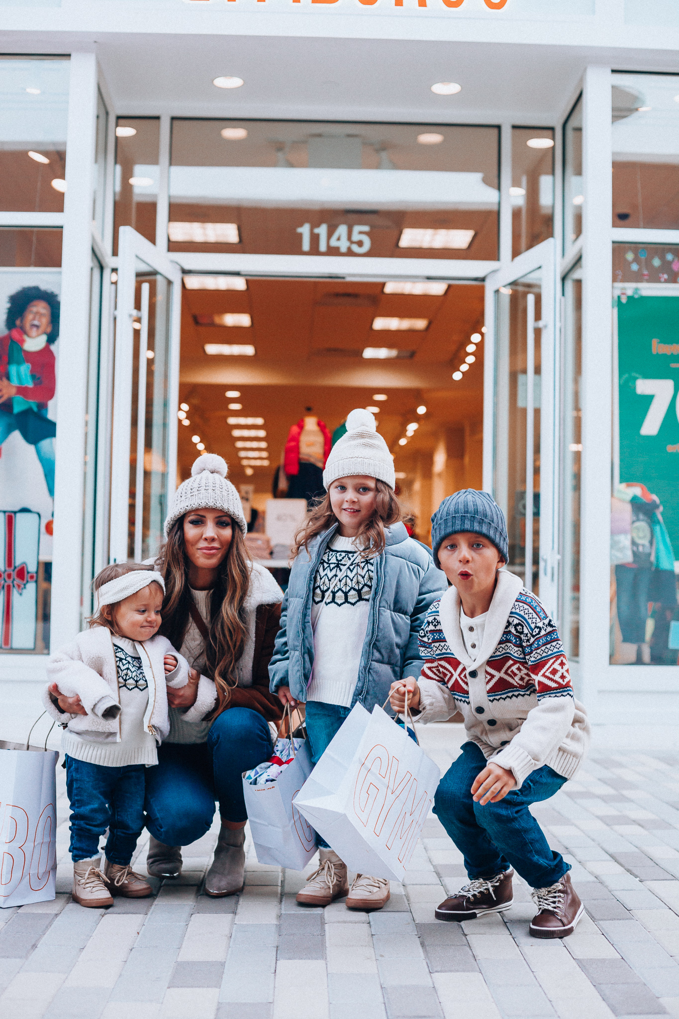 Gymboree Holiday Collection featured by top San Francisco fashion blog, The Girl in the Yellow Dress: image of a mom wearing a Abercrombie & Fitch mock neck sweater, high waist ankle jeans, Mark Fisher Chelsea boots, a pom pom beanie and a leather shoulder bag. A toddler wearing a Gymboree headband, sherpa jacket, sweater, jeggings and metallic moon boots. A boy wearing a Gymboree beanie, sweater, jeans and leather high tops. A girl wearing a Gymboree beanie, coat, sweater, jeans and boots