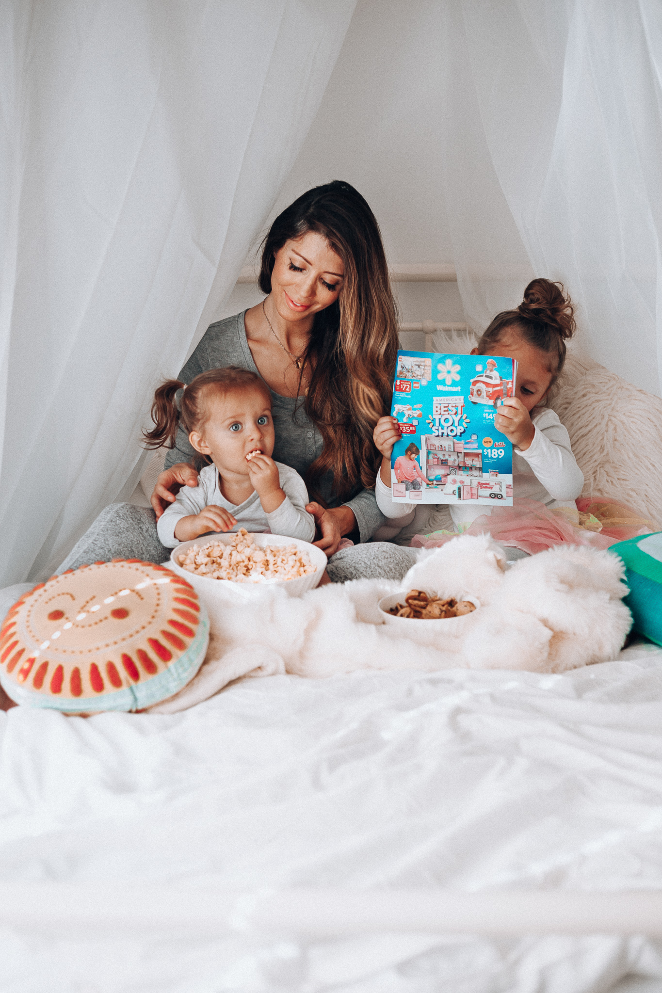 Top 15 Best Toys at Walmart featured by top San Francisco life and style blog, The Girl in the Yellow Dress: image of a mom and children looking at a Walmart toy catalogue