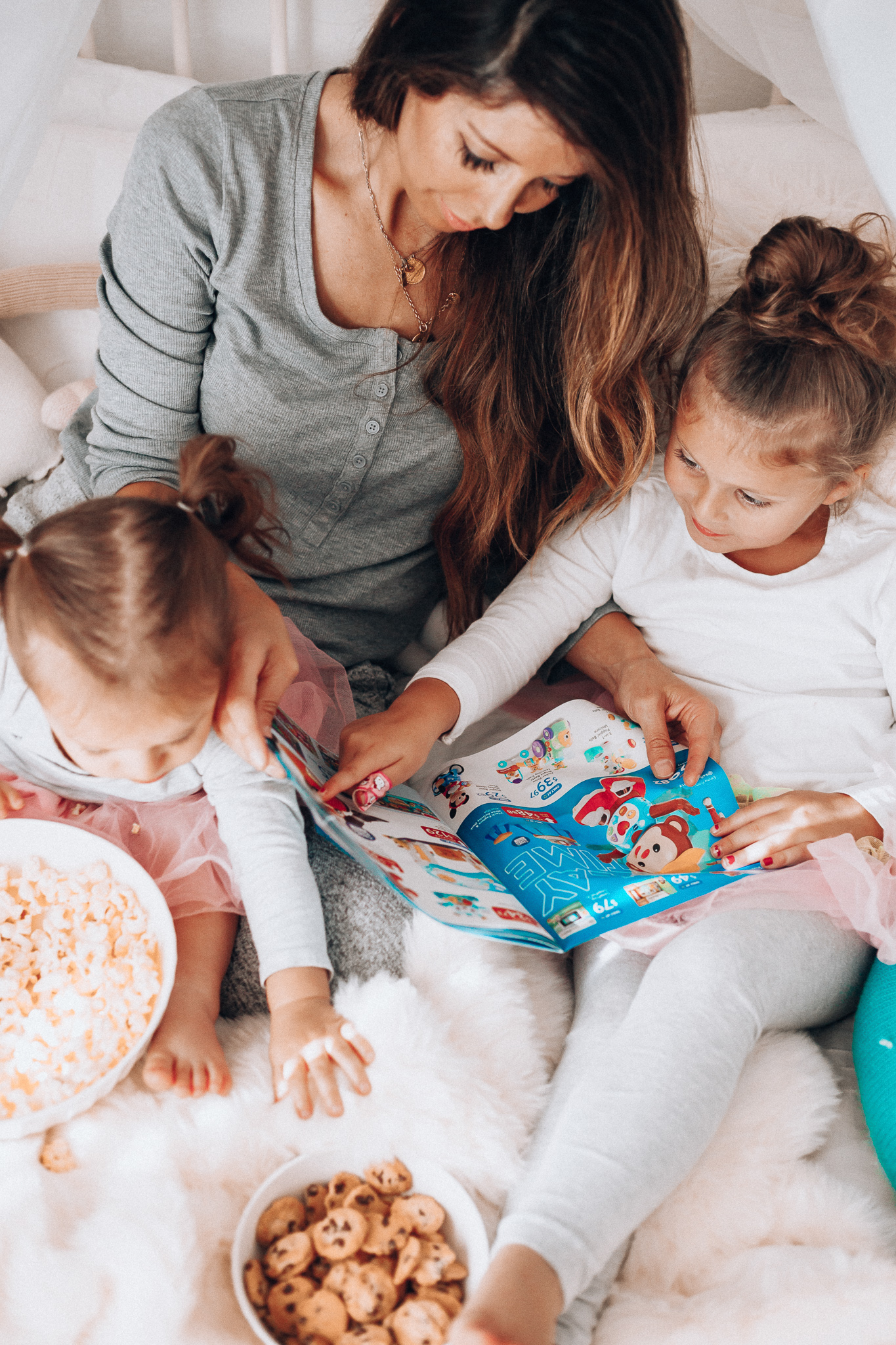 Top 15 Best Toys at Walmart featured by top San Francisco life and style blog, The Girl in the Yellow Dress: image of a mom and children looking at a Walmart toy catalogue