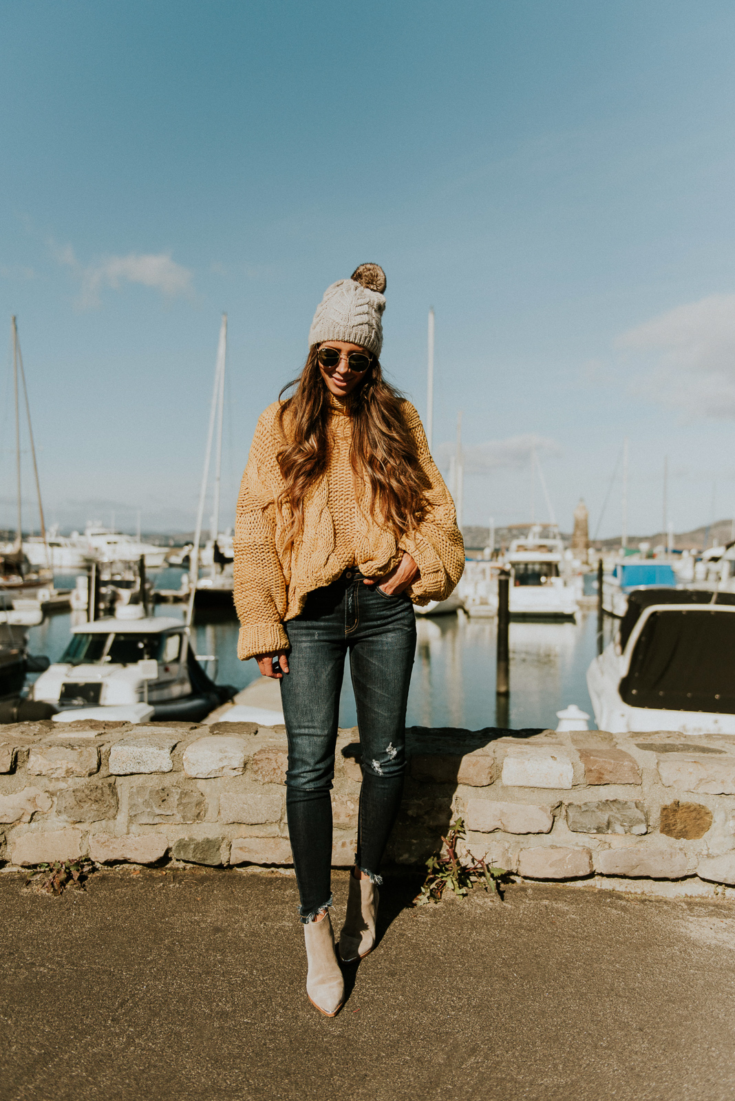 Girls Trip to San Francisco featured by top US fashion blog The Girl in the Yellow Dress; Image of woman wearing pom beanie, cable knit sweater and frayed ankle skinny jeans from Vici and Marc Fisher boots.