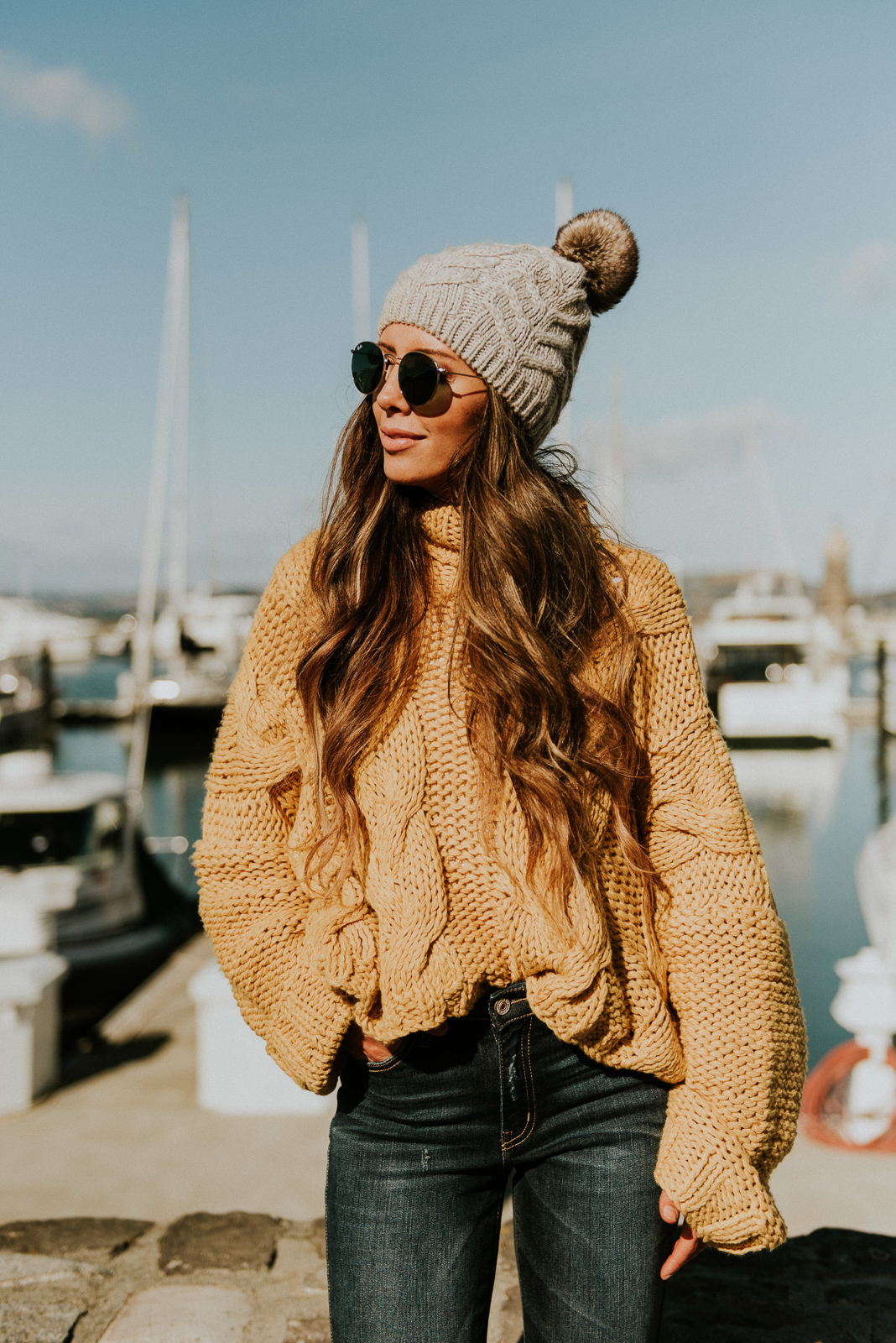 Girls Trip to San Francisco featured by top US fashion blog The Girl in the Yellow Dress; Image of woman wearing pom beanie, cable knit sweater and frayed ankle skinny jeans from Vici and Marc Fisher boots.