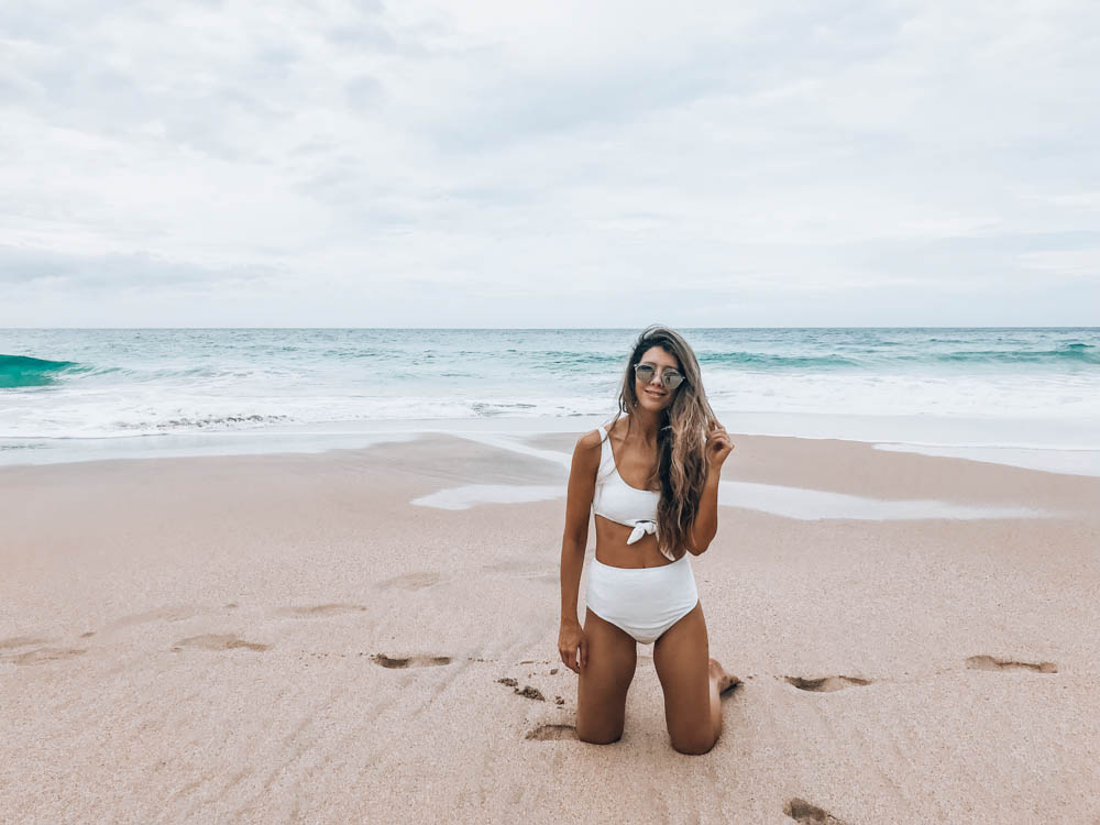 Beach Getaway featured by top US life and style blog The Girl in the Yellow Dress; Image of a woman at the beach wearing an ASOS swimsuit and Ray-Ban sunglasses.