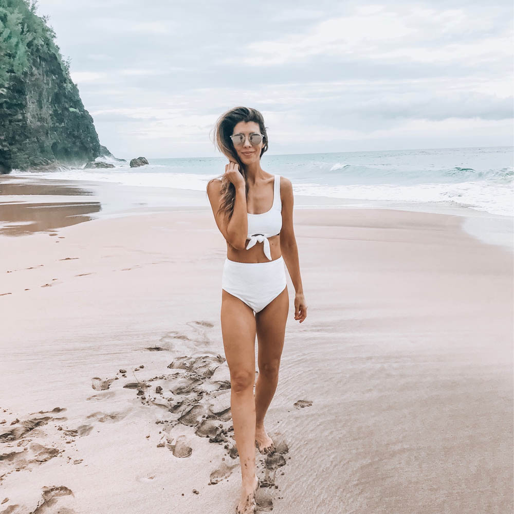 Beach Getaway featured by top US life and style blog The Girl in the Yellow Dress; Image of a woman at the beach wearing an ASOS swimsuit and Ray-Ban sunglasses.