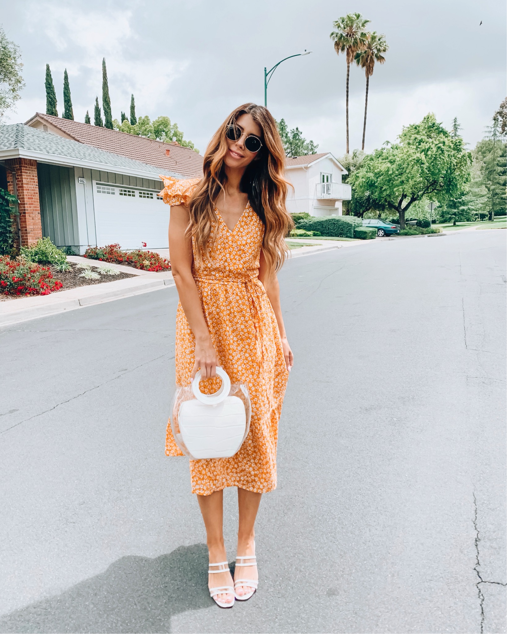 Cute Summer Dresses featured by top US fashion blog The Girl in the Yellow Dress; Image of a woman wearing an orange floral dress.
