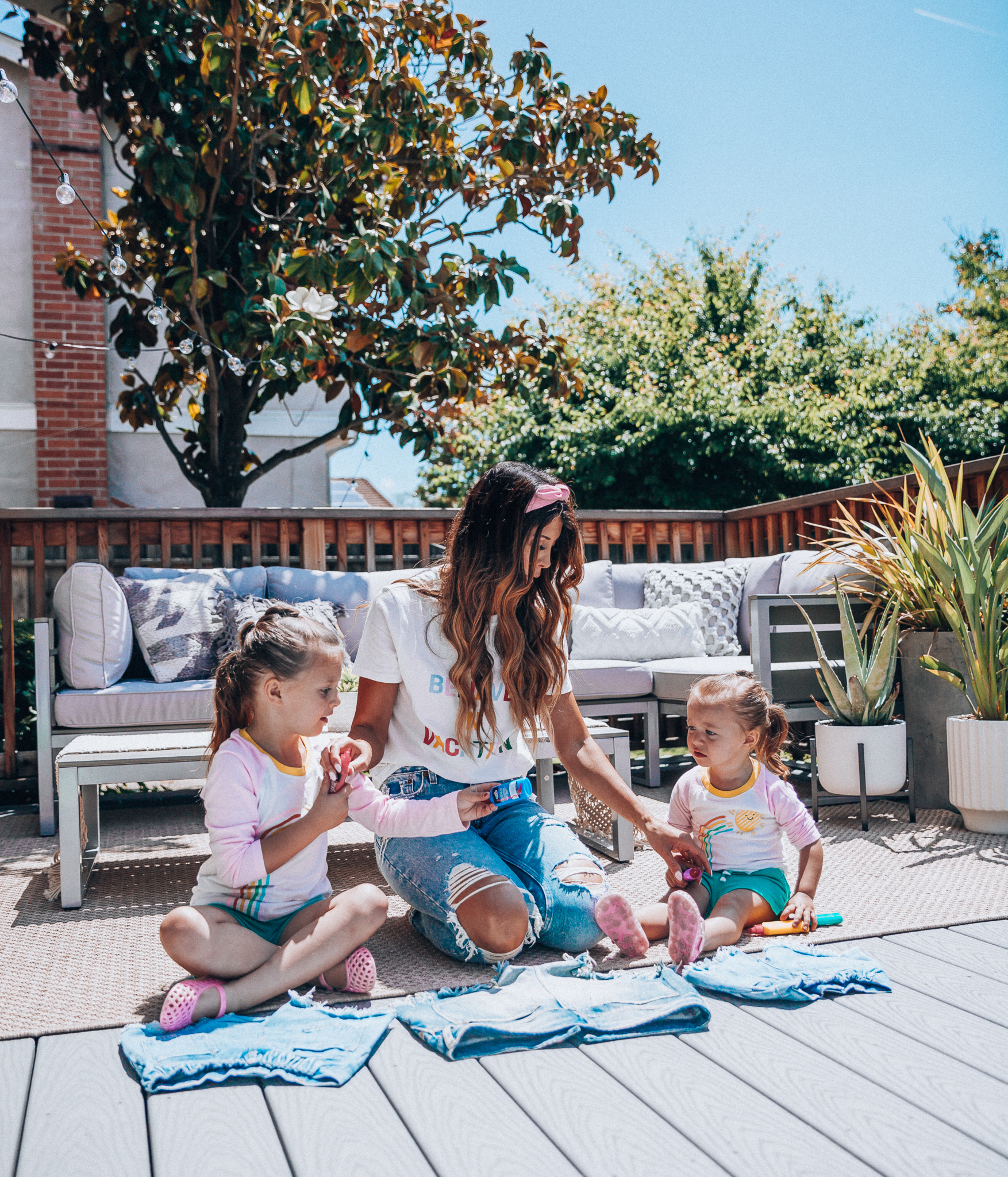 The Girl in the Yellow Dress | Latisha Springer | Fun Summer Activities for Kids by top US mom blog, The Girl in the Yellow Dress: image of mom with young girls sitting on back porch decorating cutoff denim shorts with puff paint.