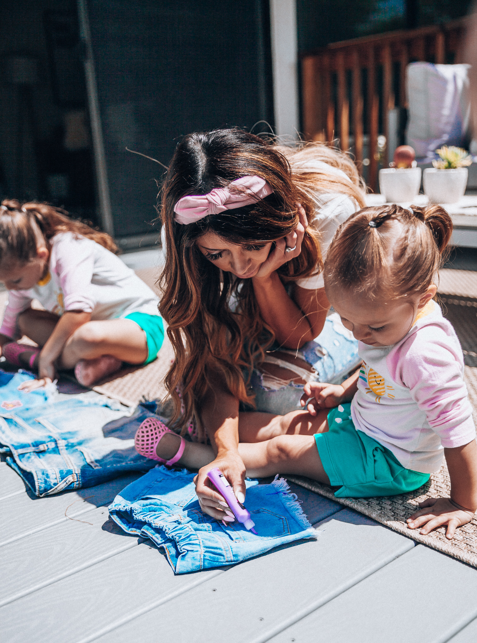 The Girl in the Yellow Dress | Latisha Springer | Fun Summer Activities for Kids by top US mom blog, The Girl in the Yellow Dress: image of mom with young girls sitting on back porch deck decorating cutoff denim shorts with puff paint.