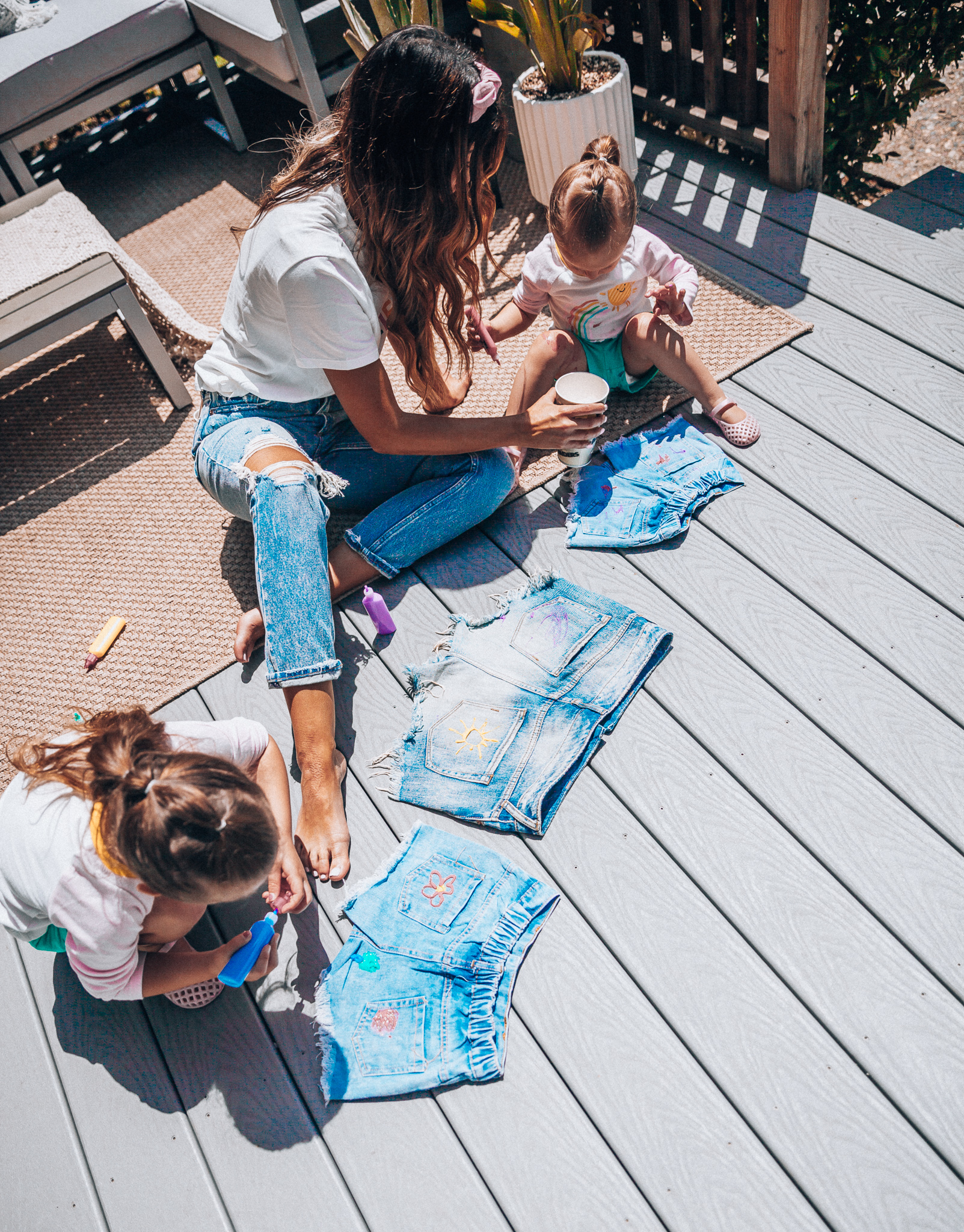 The Girl in the Yellow Dress | Latisha Springer | Fun Summer Activities for Kids by top US mom blog, The Girl in the Yellow Dress: image mom with young girl sitting on back porch deck decorating cutoff denim shorts with puff paint.