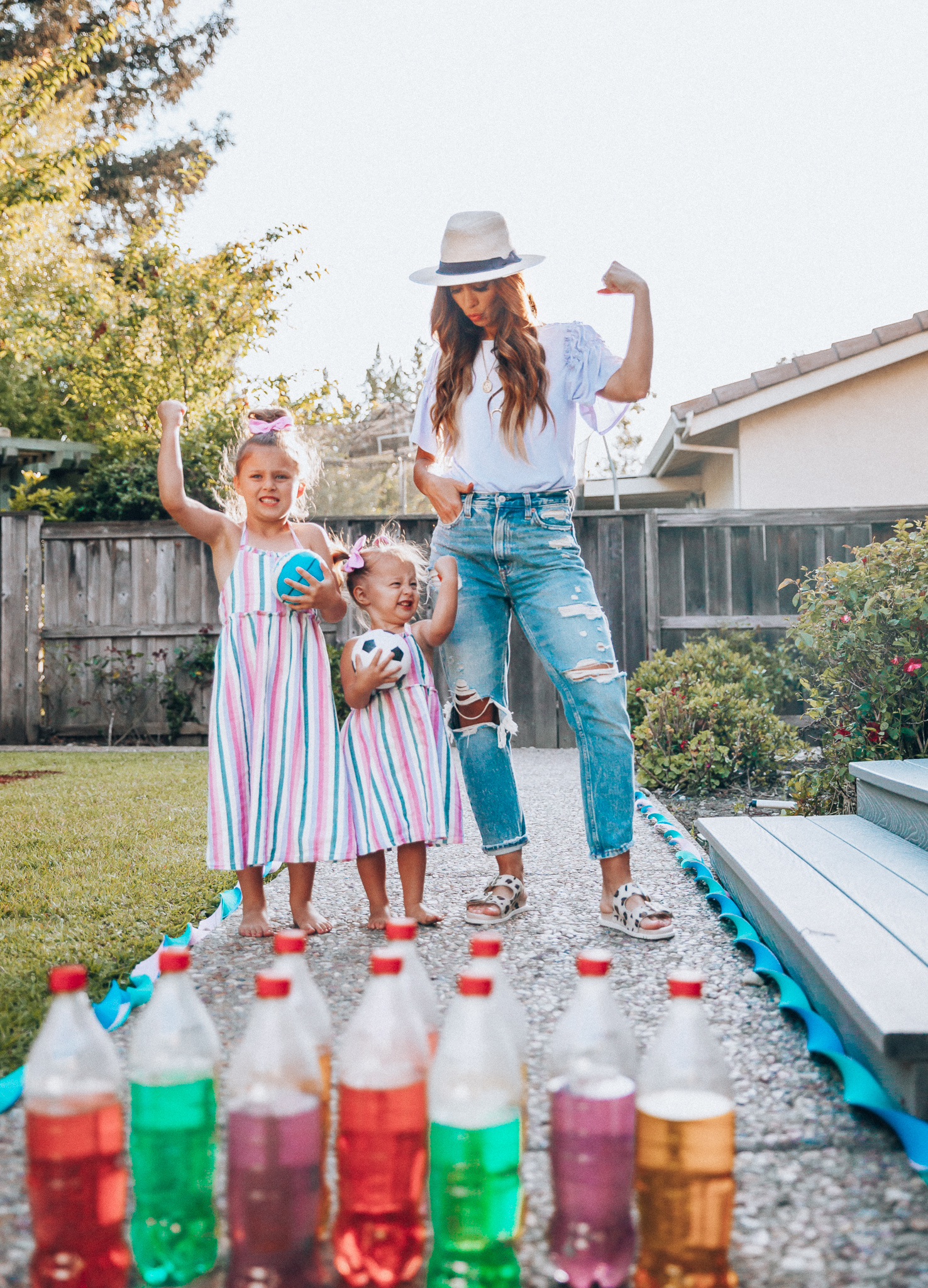 Fun Summer Activities for Kids-Part 2 by popular mom blog The Girl in the Yellow Dress: image of woman and two young girls playing outdoor bowling.  Woman is wearing a Brixton Joanna Straw Hat, Naughty Monkey Women's Hey Pony Sandal, Abercrombie and Fitch Boyfriend jeans, and a Nordstrom ruffle sleeve top.  Girls are wearing an Oldnavy Striped Ruffle-Trim Halter Midi Dress. 