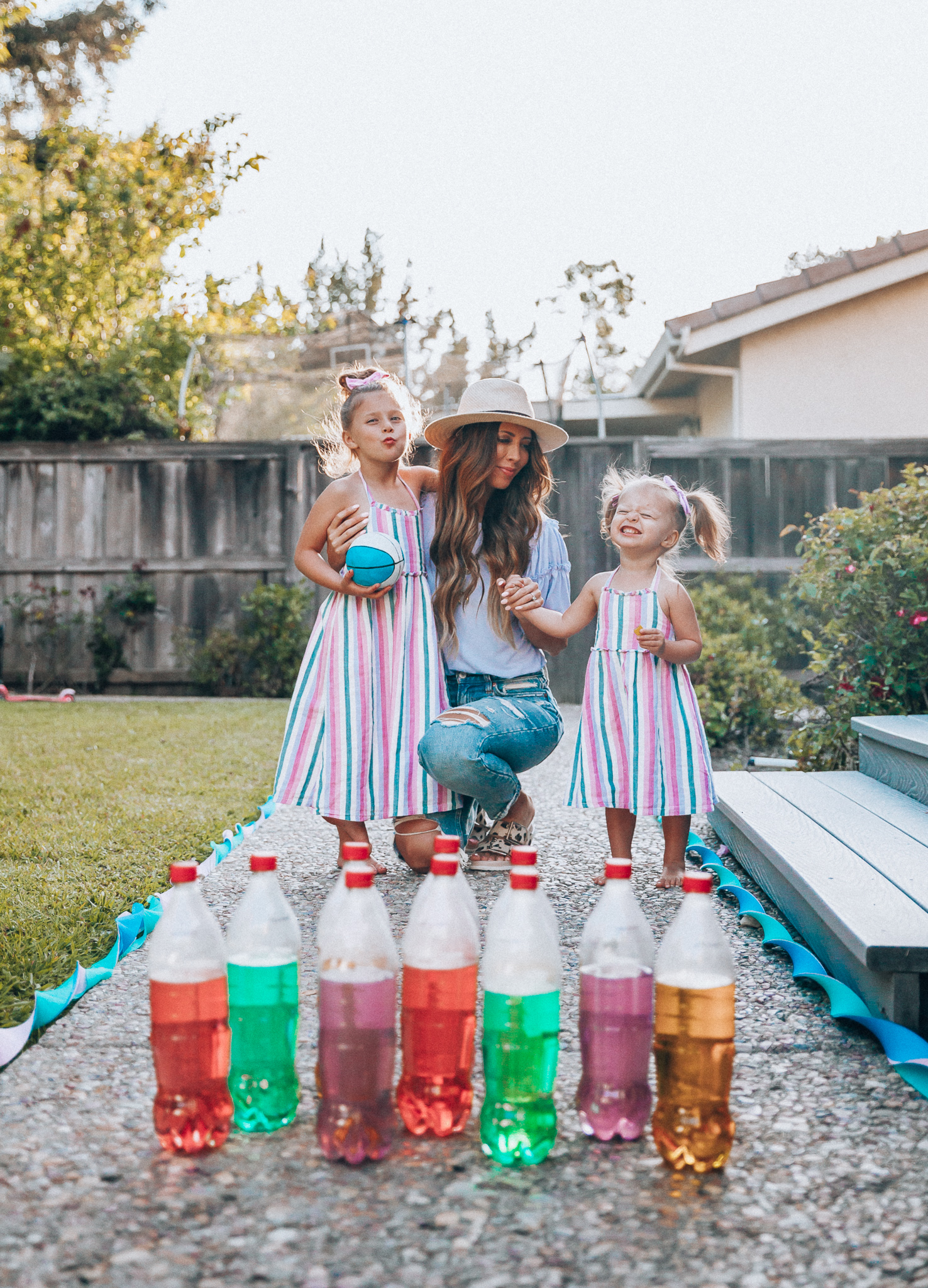 Fun Summer Activities for Kids-Part 2 by popular mom blog The Girl in the Yellow Dress: image of woman and two young girls playing outdoor bowling.  Woman is wearing a Brixton Joanna Straw Hat, Naughty Monkey Women's Hey Pony Sandal, Abercrombie and Fitch Boyfriend jeans, and a Nordstrom ruffle sleeve top.  Girls are wearing an Oldnavy Striped Ruffle-Trim Halter Midi Dress. 