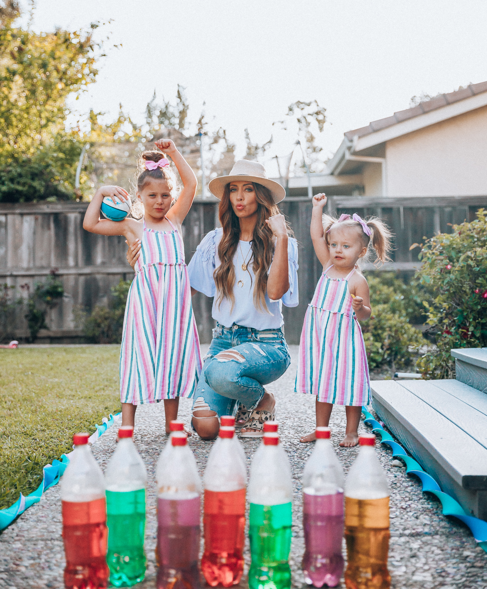 Fun Summer Activities for Kids-Part 2 by popular mom blog The Girl in the Yellow Dress: image of woman and two young girls playing outdoor bowling.  Woman is wearing a Brixton Joanna Straw Hat, Naughty Monkey Women's Hey Pony Sandal, Abercrombie and Fitch Boyfriend jeans, and a Nordstrom ruffle sleeve top.  Girls are wearing an Oldnavy Striped Ruffle-Trim Halter Midi Dress. 