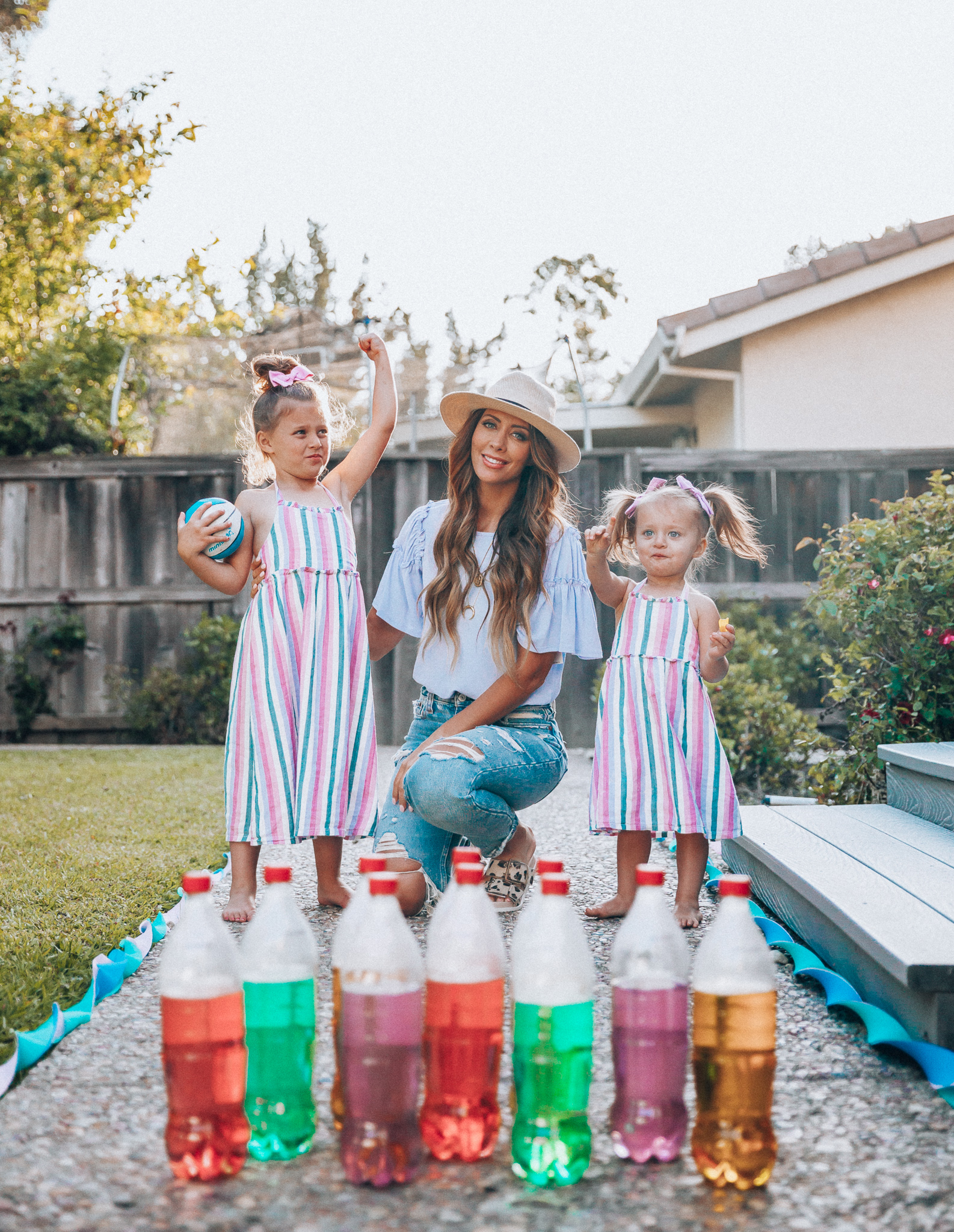 Fun Summer Activities for Kids-Part 2 by popular mom blog The Girl in the Yellow Dress: image of woman and two young girls playing outdoor bowling.  Woman is wearing a Brixton Joanna Straw Hat, Naughty Monkey Women's Hey Pony Sandal, Abercrombie and Fitch Boyfriend jeans, and a Nordstrom ruffle sleeve top.  Girls are wearing an Oldnavy Striped Ruffle-Trim Halter Midi Dress. 