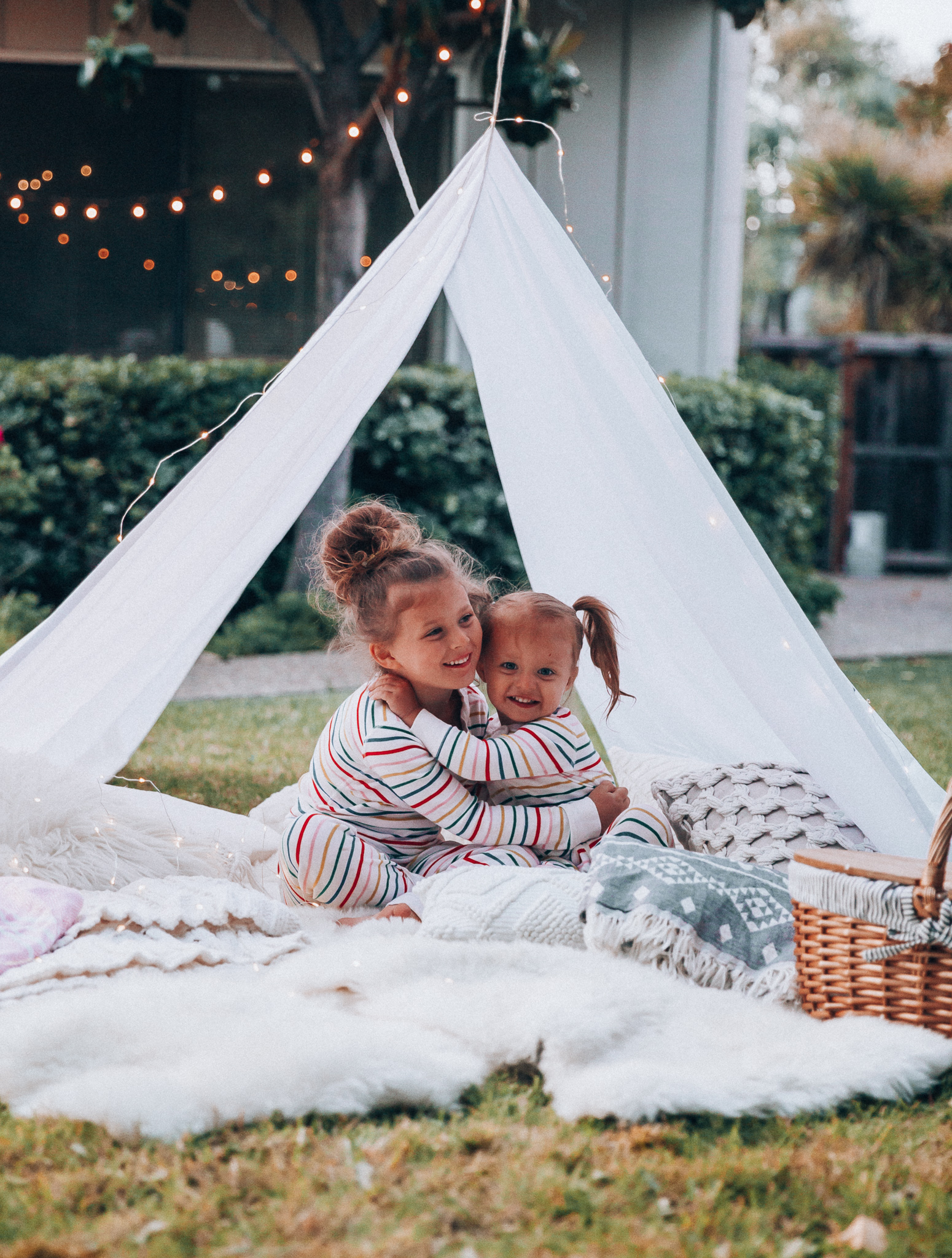 Fun Summer Activities for Kids-Part 2 by popular mom blog The Girl in the Yellow Dress: image of woman and two young girls having an outdoor picnic with their Picnic Time Country Picnic Basket in a white tent.  Woman is wearing an Ivory Aerie Arlo Pocket Tee and Aerie Plush Harem Jogger.  The two young girls are wearing Hanna Andersson Long John Pajamas In Organic Cotton.