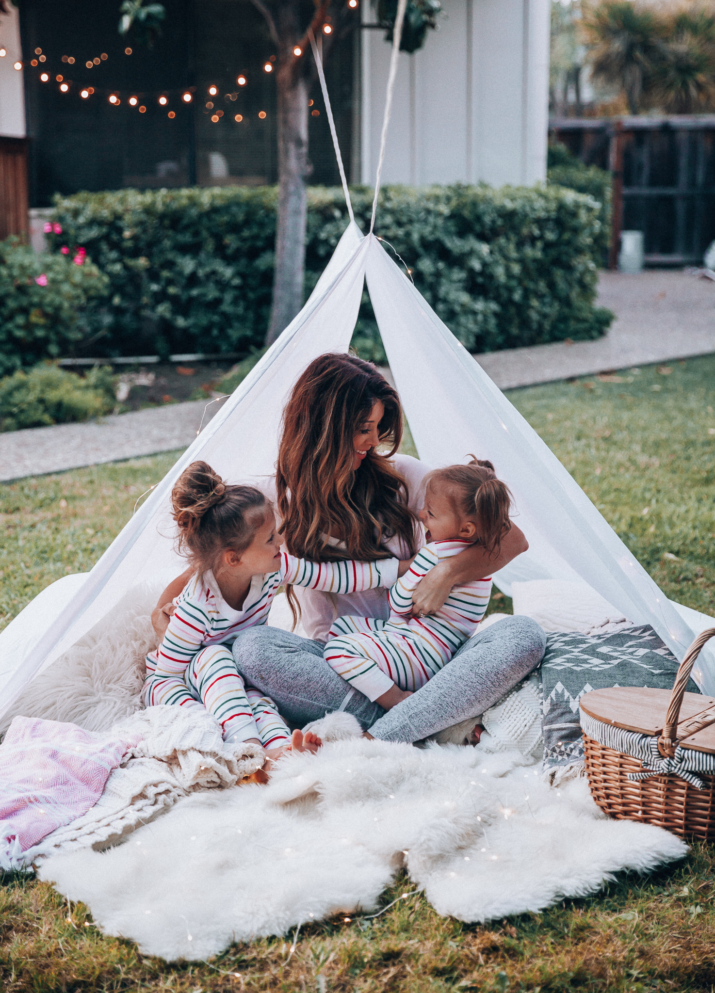 Fun Summer Activities for Kids-Part 2 by popular mom blog The Girl in the Yellow Dress: image of woman and two young girls having an outdoor picnic with their Picnic Time Country Picnic Basket in a white tent.  Woman is wearing an Ivory Aerie Arlo Pocket Tee and Aerie Plush Harem Jogger.  The two young girls are wearing Hanna Andersson Long John Pajamas In Organic Cotton.