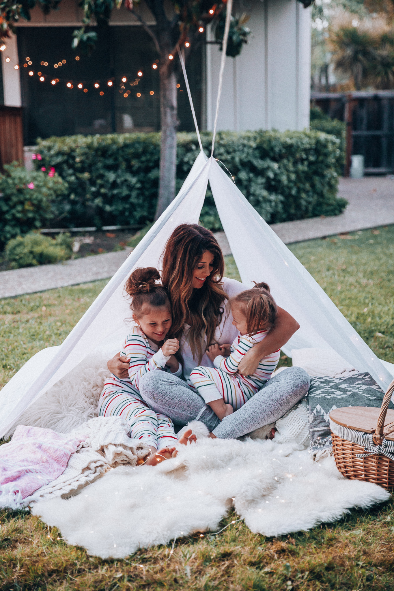 Fun Summer Activities for Kids-Part 2 by popular mom blog The Girl in the Yellow Dress: image of woman and two young girls having an outdoor picnic with their Picnic Time Country Picnic Basket in a white tent.  Woman is wearing an Ivory Aerie Arlo Pocket Tee and Aerie Plush Harem Jogger.  The two young girls are wearing Hanna Andersson Long John Pajamas In Organic Cotton.