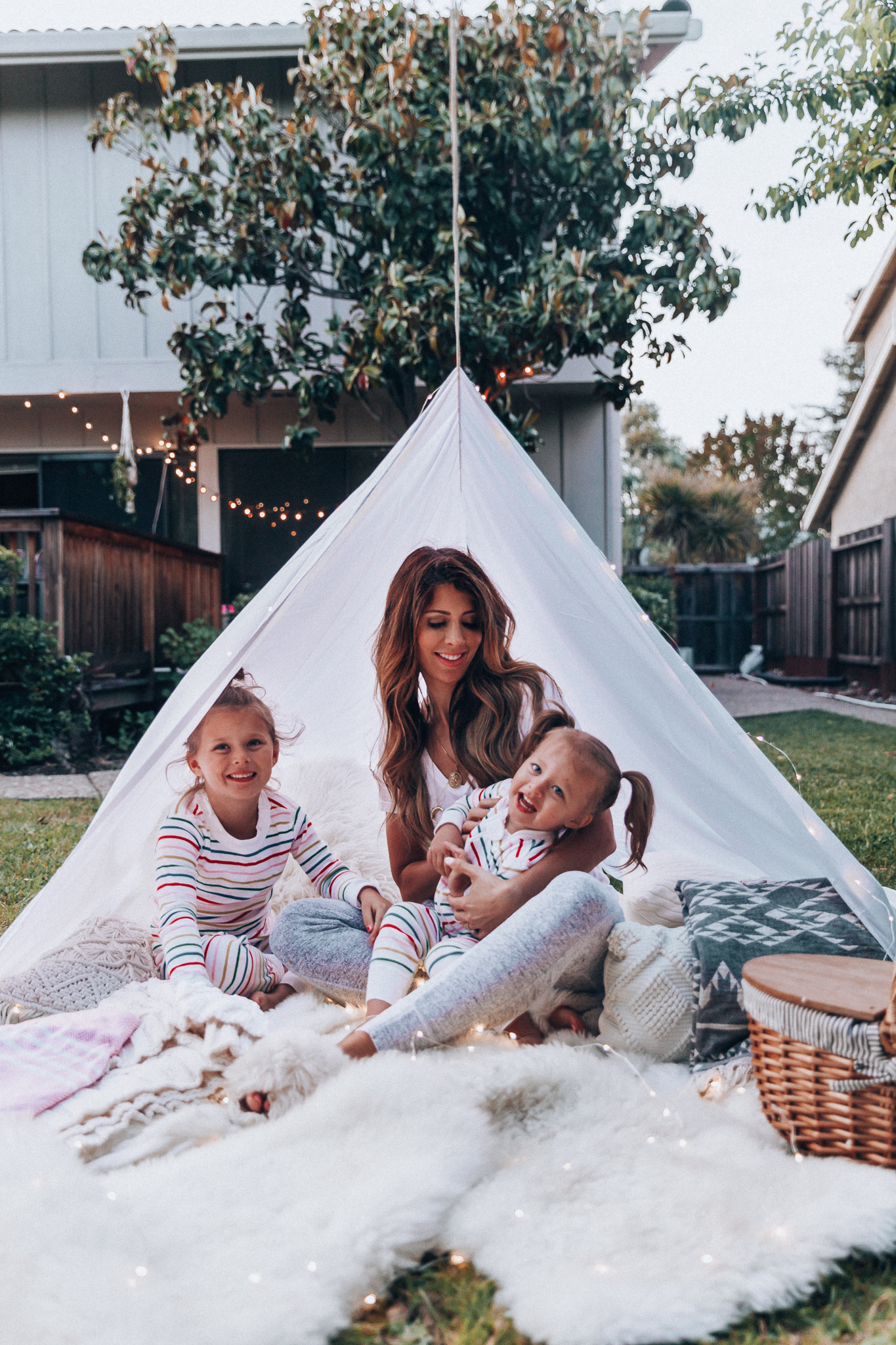 Fun Summer Activities for Kids-Part 2 by popular mom blog The Girl in the Yellow Dress: image of woman and two young girls having an outdoor picnic with their Picnic Time Country Picnic Basket in a white tent.  Woman is wearing an Ivory Aerie Arlo Pocket Tee and Aerie Plush Harem Jogger.  The two young girls are wearing Hanna Andersson Long John Pajamas In Organic Cotton.