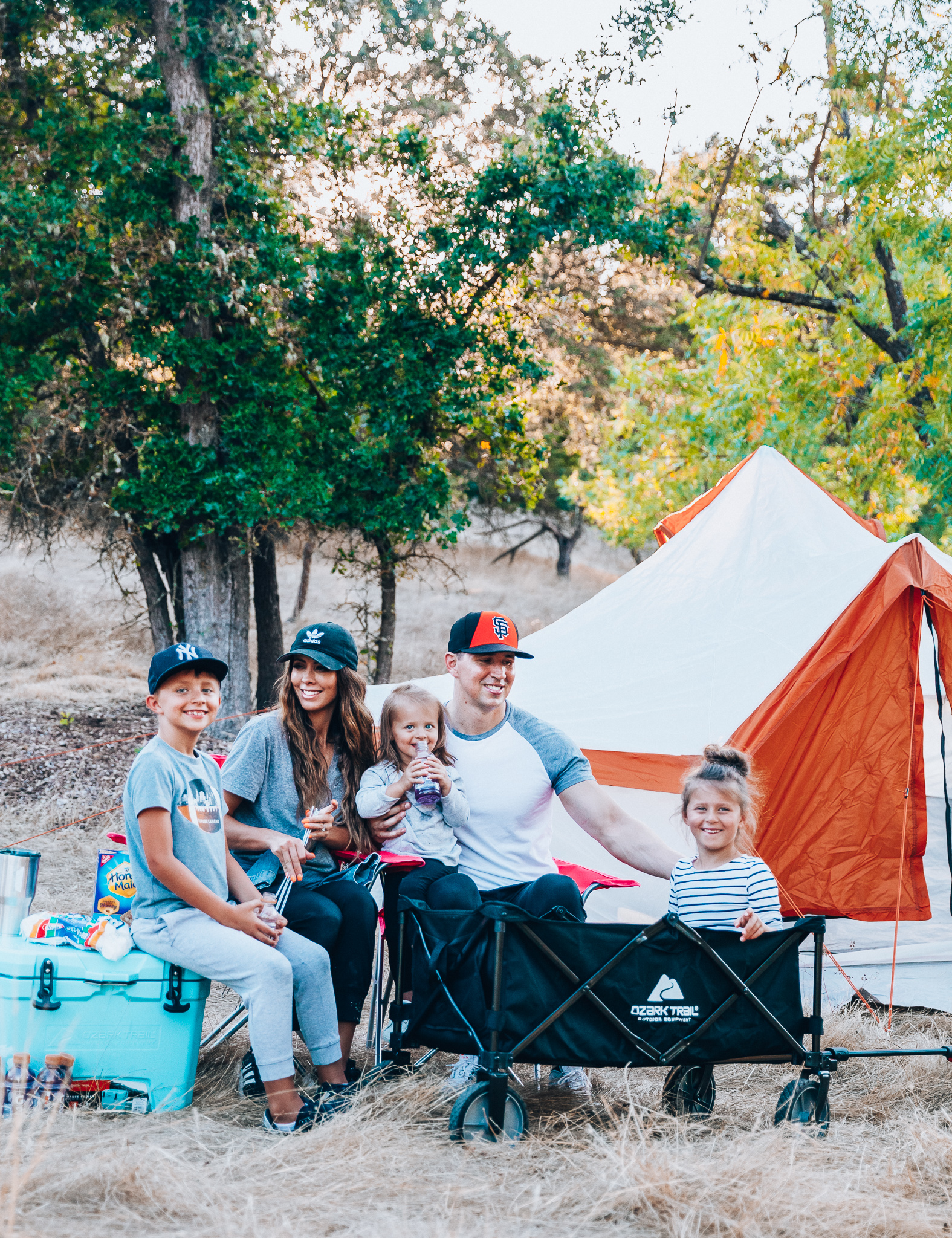 Ozark Trail with Walmart by popular San Francisco life and style blog, The Girl in the Yellow Dress: image of a family outside camping with an Ozark Trail, 8 Person Yurt Camping Tent, Ozark Trail Folding Multipurpose Wagon, Ozark Trail Oversize Mesh Folding Camping Chair, Ozark Trail 26-Quart High-Performance Cooler, Ozark Trail 30-Ounce Double-Wall, Vacuum-Sealed Tumbler, and Ozark Trail Outdoor Equipment 400 Lumen LED Camping Lantern from Walmart.