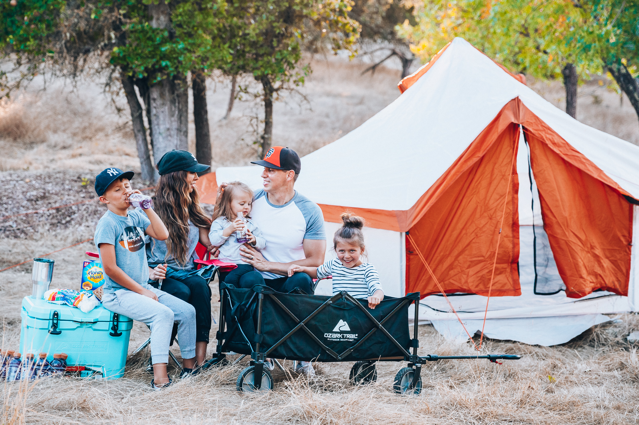 Ozark Trail with Walmart by popular San Francisco life and style blog, The Girl in the Yellow Dress: image of a family outside camping with an Ozark Trail, 8 Person Yurt Camping Tent, Ozark Trail Folding Multipurpose Wagon, Ozark Trail Oversize Mesh Folding Camping Chair, Ozark Trail 26-Quart High-Performance Cooler, Ozark Trail 30-Ounce Double-Wall, Vacuum-Sealed Tumbler, and Ozark Trail Outdoor Equipment 400 Lumen LED Camping Lantern from Walmart.