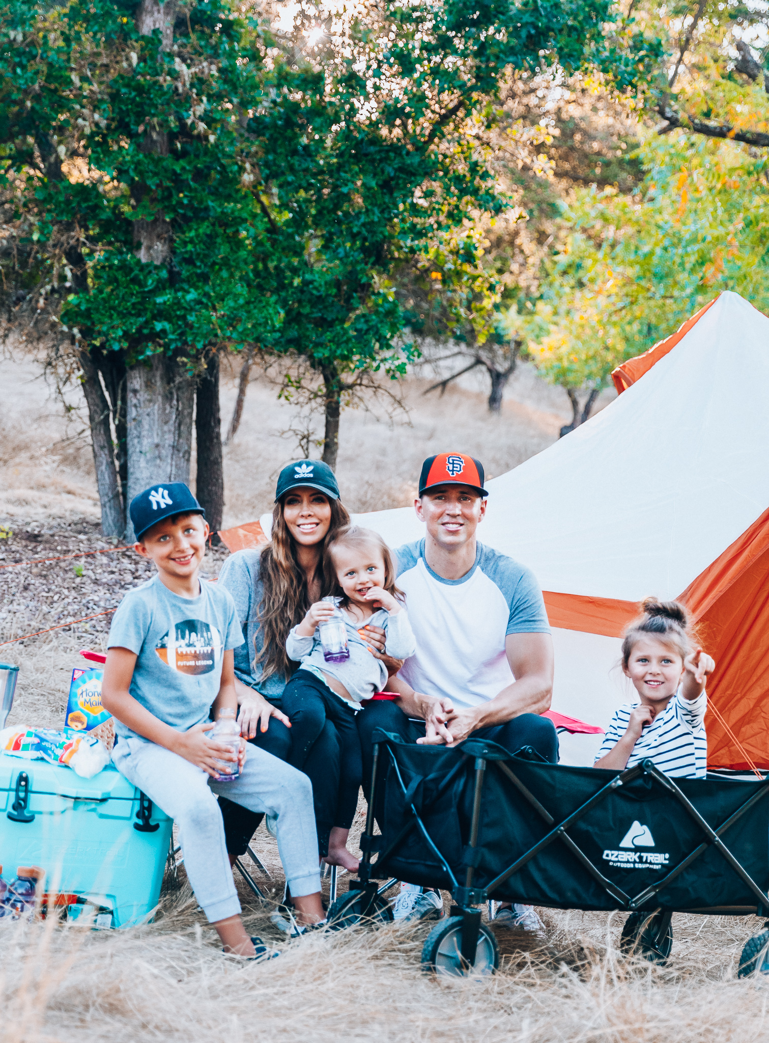 Ozark Trail with Walmart by popular San Francisco life and style blog, The Girl in the Yellow Dress: image of a family outside camping with an Ozark Trail, 8 Person Yurt Camping Tent, Ozark Trail Folding Multipurpose Wagon, Ozark Trail Oversize Mesh Folding Camping Chair, Ozark Trail 26-Quart High-Performance Cooler, Ozark Trail 30-Ounce Double-Wall, Vacuum-Sealed Tumbler, and Ozark Trail Outdoor Equipment 400 Lumen LED Camping Lantern from Walmart.