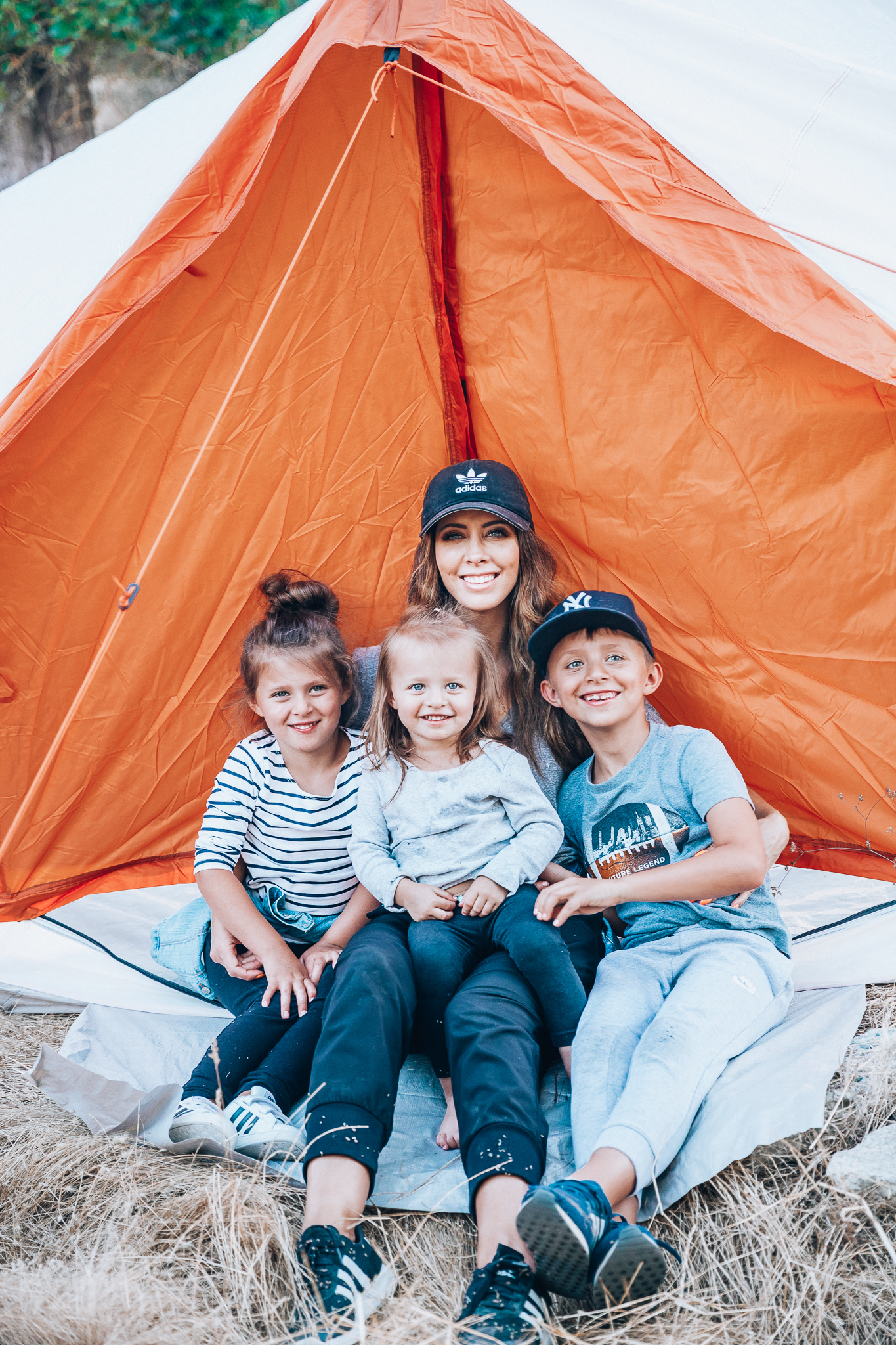 Ozark Trail with Walmart by popular San Francisco life and style blog, The Girl in the Yellow Dress: image of a mom and her three kids sitting in an Ozark Trail, 8 Person Yurt Camping Tent from Walmart.