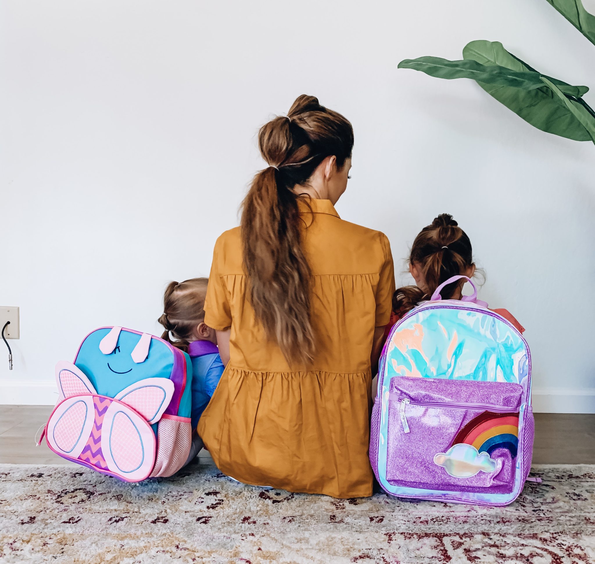 Back To School Shopping Essentials On a Budget! by popular San Francisco life and style blog, The Girl in the Yellow Dress: image of a mom and her two daughters sitting on the floor and wearing a Walmart Time and Tru Women's Tiered Button Front Top, Nordstrom J Brand 9326 Low Rise Crop Skinny Jeans, Evereve Dolce Vita Nelly Leopard Slide, Target Cat and Jack Toddler Girls' Wintex solid Tank Top, Target Cat and Jack Toddler Girls' Bike Shorts, Walmart Wonder Nation Foil Rainbow Backpack, and Walmart Wonder Nation Wonder Nation Butterfly Critter Backpack. 