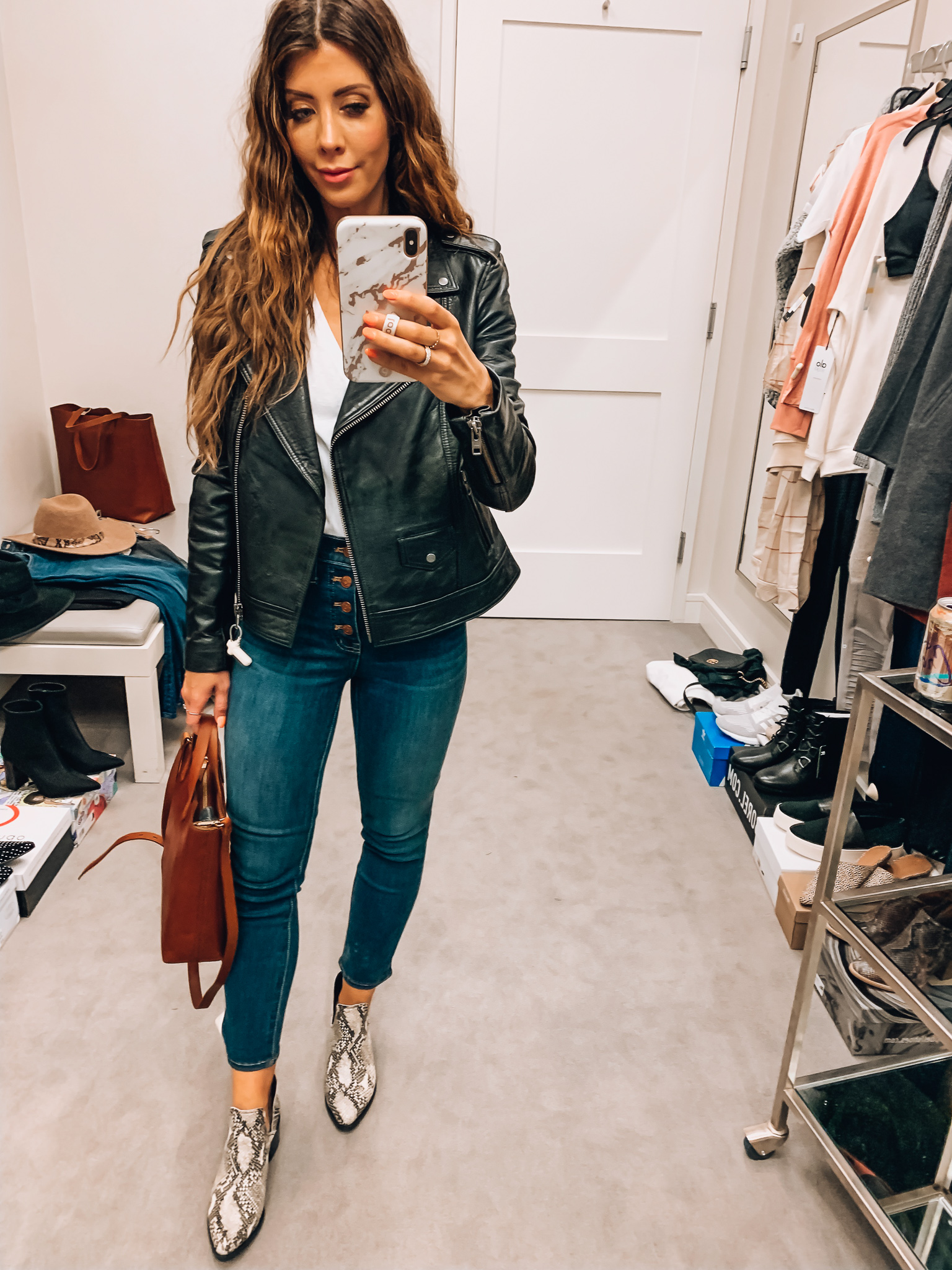 Nordstrom Anniversary Sale Early Access! by popular San Francisco fashion blog, The Girl in the Yellow Dress: image of a woman standing inside a Nordstrom dressing room wearing a BP. V-Neck Tee, Treasure and Bond Leather Biker Jacket, Madewell 10-Inch High Waist Skinny Jeans: Button Front Edition, Blondo Eliza Waterproof Bootie, and Madewell Small Transport Leather Crossbody Tote