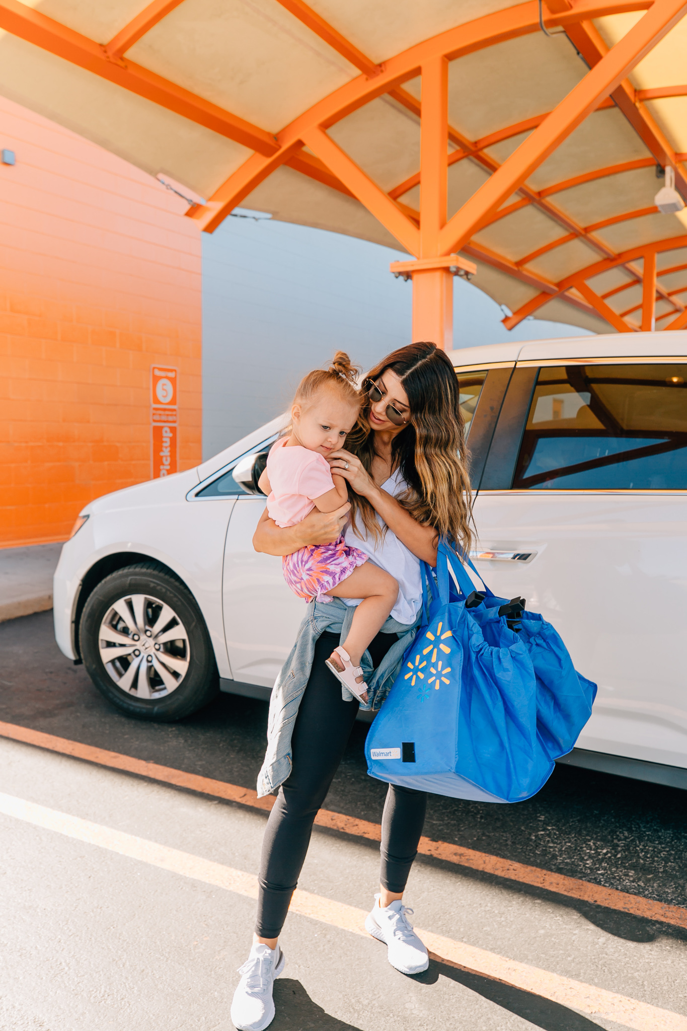 Walmart Grocery Pick Up Review! by popular San Francisco lifestyle blog, The Girl in the Yellow Dress: image of a mom holding her daughter outside in front of the Walmart grocery pick-up.