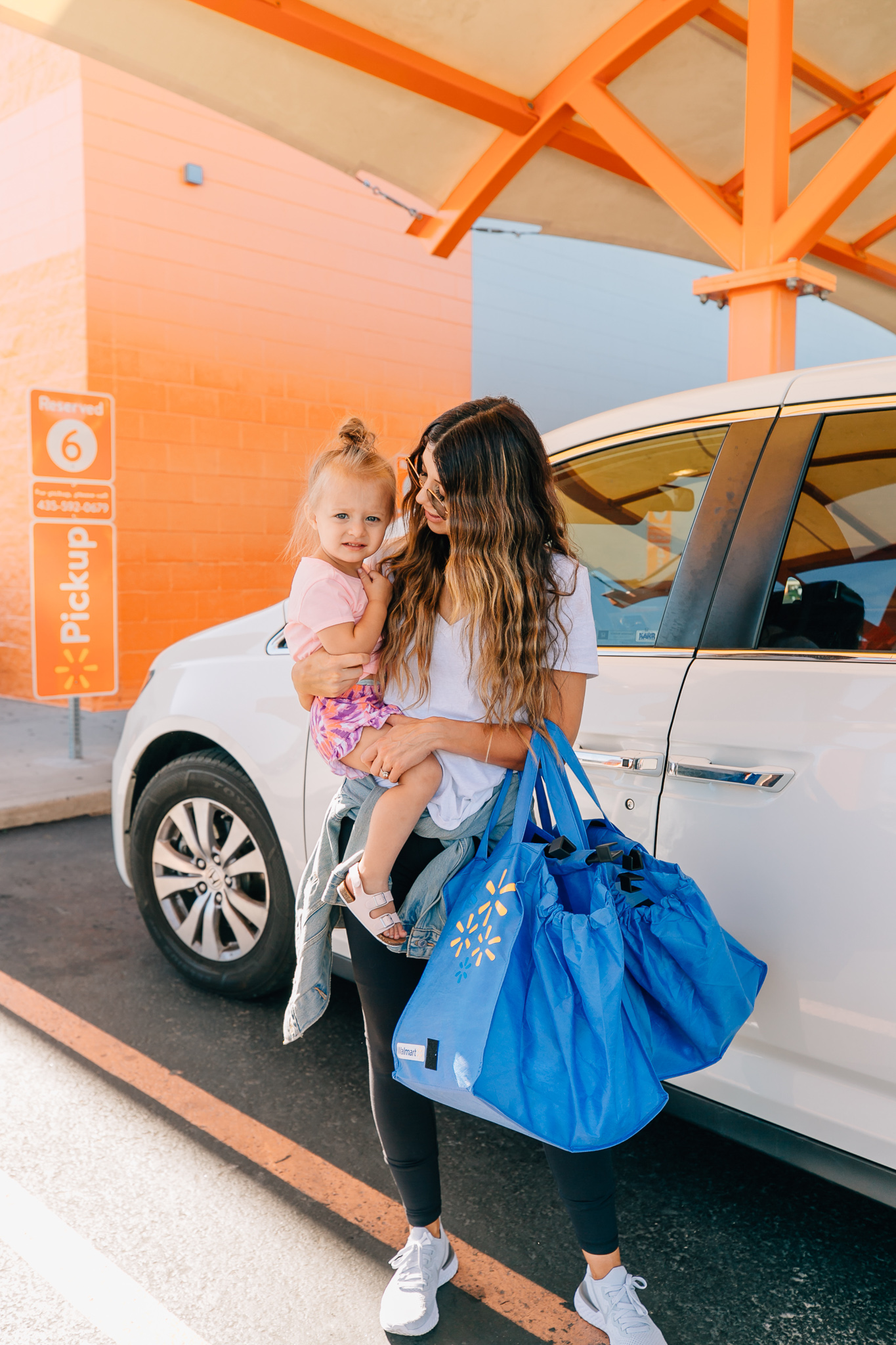 Walmart Grocery Pick Up Review! by popular San Francisco lifestyle blog, The Girl in the Yellow Dress: image of a mom holding her daughter outside in front of the Walmart grocery pick-up.