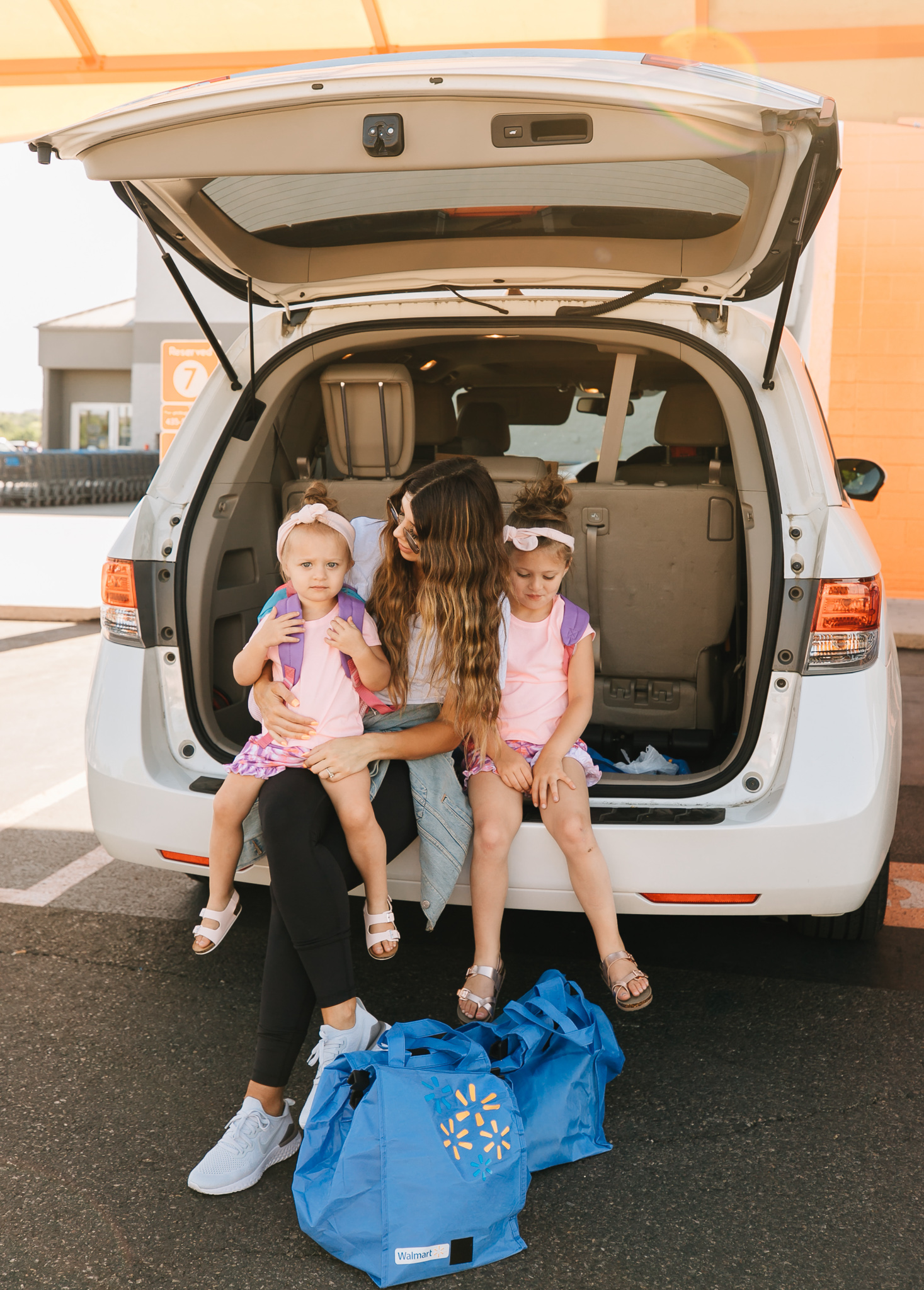 Walmart Grocery Pick Up Review! by popular San Francisco lifestyle blog, The Girl in the Yellow Dress: image of a mom and her two daughters sitting in the back of their car at the Walmart grocery pick-up.