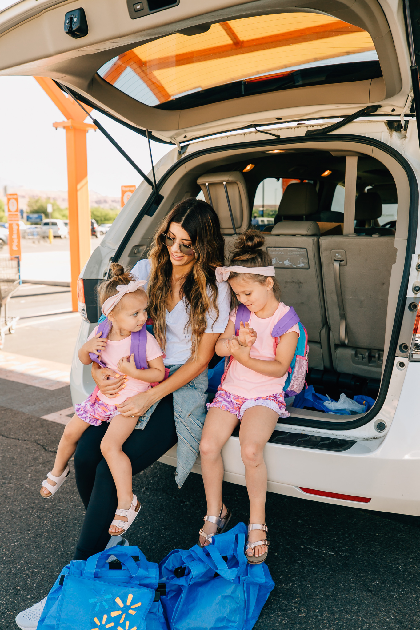 Walmart Grocery Pick Up Review! by popular San Francisco lifestyle blog, The Girl in the Yellow Dress: image of a mom and her two daughters sitting in the back of their car at the Walmart grocery pick-up.