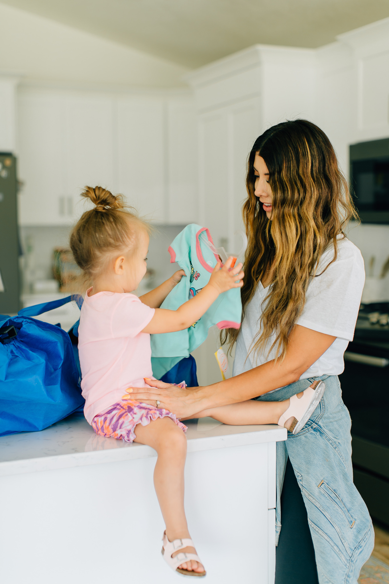 Walmart Grocery Pick Up Review! by popular San Francisco lifestyle blog, The Girl in the Yellow Dress: image of a mom inside her kitchen with her daughter and looking at the items they purchased from Walmart.