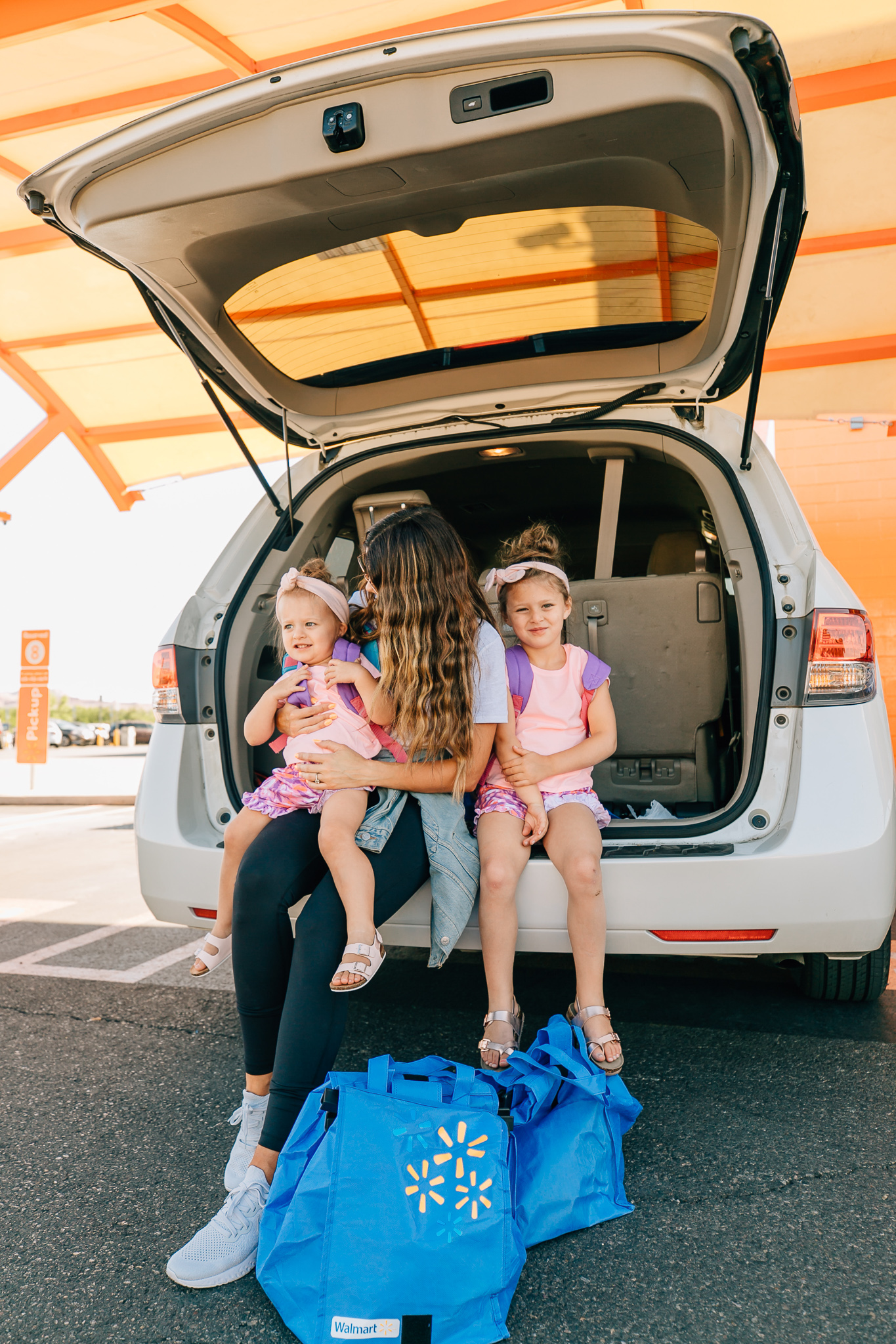 Walmart Grocery Pick Up Review! by popular San Francisco lifestyle blog, The Girl in the Yellow Dress: image of a mom and her two daughters sitting in the back of their car at the Walmart grocery pick-up.