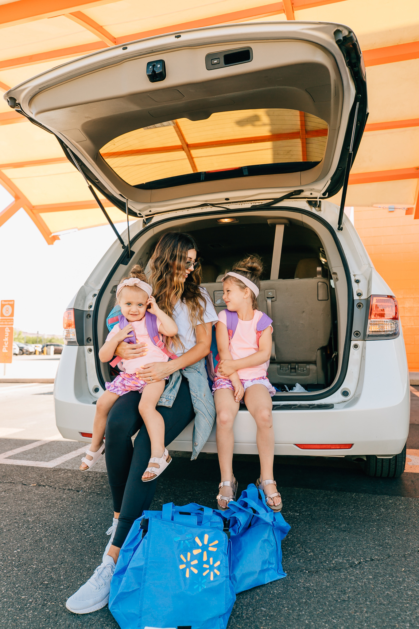 Walmart Grocery Pick Up Review! by popular San Francisco lifestyle blog, The Girl in the Yellow Dress: image of a mom and her two daughters sitting in the back of their car at the Walmart grocery pick-up.