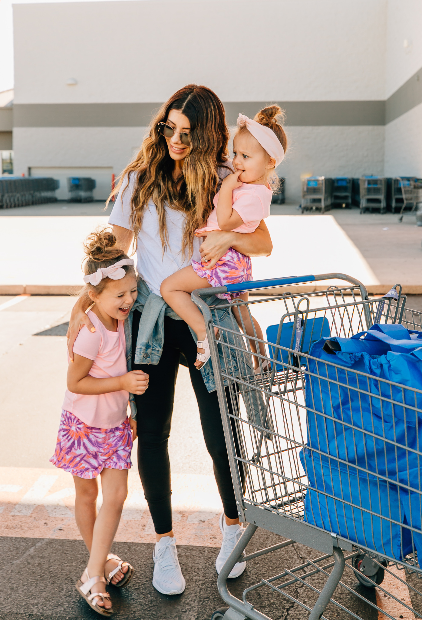 Walmart Grocery Pick Up Review! by popular San Francisco lifestyle blog, The Girl in the Yellow Dress: image of a mom and her two daughters pushing a shopping cart outside in front of the Walmart grocery pick-up.