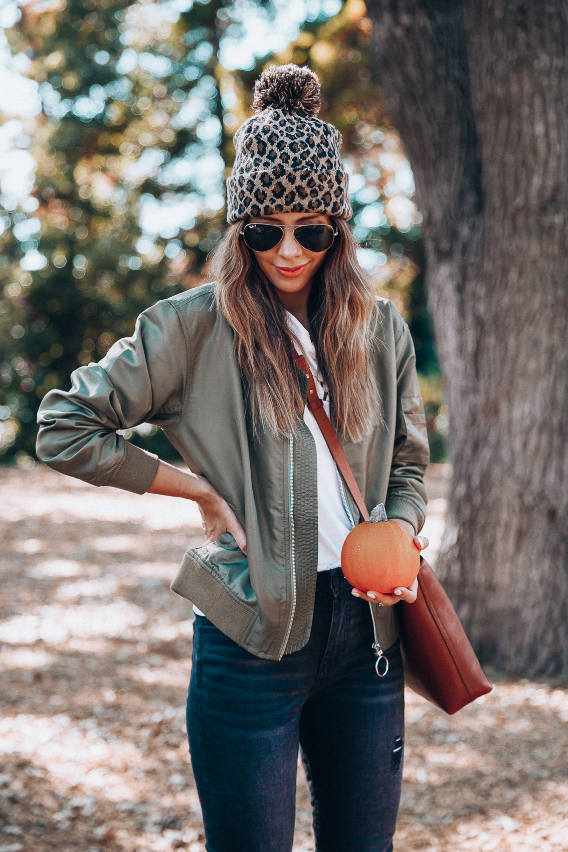 4 Fall Trends to Try by popular San Francisco fashion blog, The Girl in the Yellow Dress: image of a woman standing outside in a pile of leaves and wearing a Sole Society LEOPARD BEANIE W/ POM, EverEve Good American Bomber Jacket, Nordstrom Top Shop Jamie High Waist Ripped Hem Skinny Jeans, Evereve Sorel Blake Lace Up Bootie, Nordstrom Ray-Ban Standard Original 58mm Aviator Sunglasses, and Evereve Sol Angeles Grateful Tee.