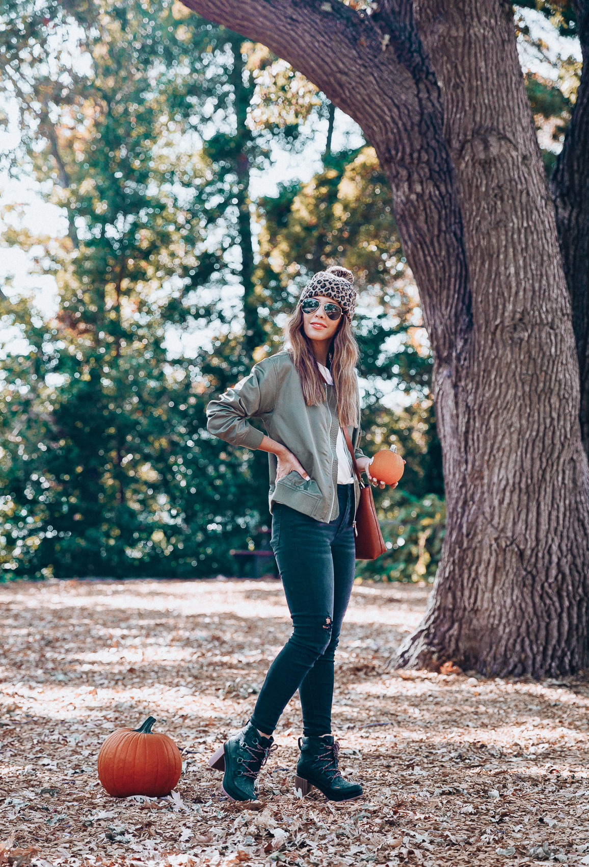 4 Fall Trends to Try by popular San Francisco fashion blog, The Girl in the Yellow Dress: image of a woman standing outside in a pile of leaves and wearing a Sole Society LEOPARD BEANIE W/ POM, EverEve Good American Bomber Jacket, Nordstrom Top Shop Jamie High Waist Ripped Hem Skinny Jeans, Evereve Sorel Blake Lace Up Bootie, Nordstrom Ray-Ban Standard Original 58mm Aviator Sunglasses, and Evereve Sol Angeles Grateful Tee.