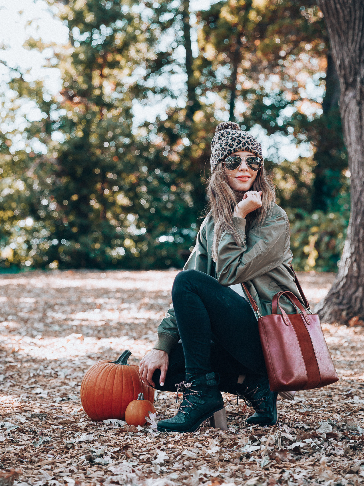 4 Fall Trends to Try by popular San Francisco fashion blog, The Girl in the Yellow Dress: image of a woman standing outside in a pile of leaves and wearing a Sole Society LEOPARD BEANIE W/ POM, EverEve Good American Bomber Jacket, Nordstrom Top Shop Jamie High Waist Ripped Hem Skinny Jeans, Evereve Sorel Blake Lace Up Bootie, Nordstrom Ray-Ban Standard Original 58mm Aviator Sunglasses, and Evereve Sol Angeles Grateful Tee.