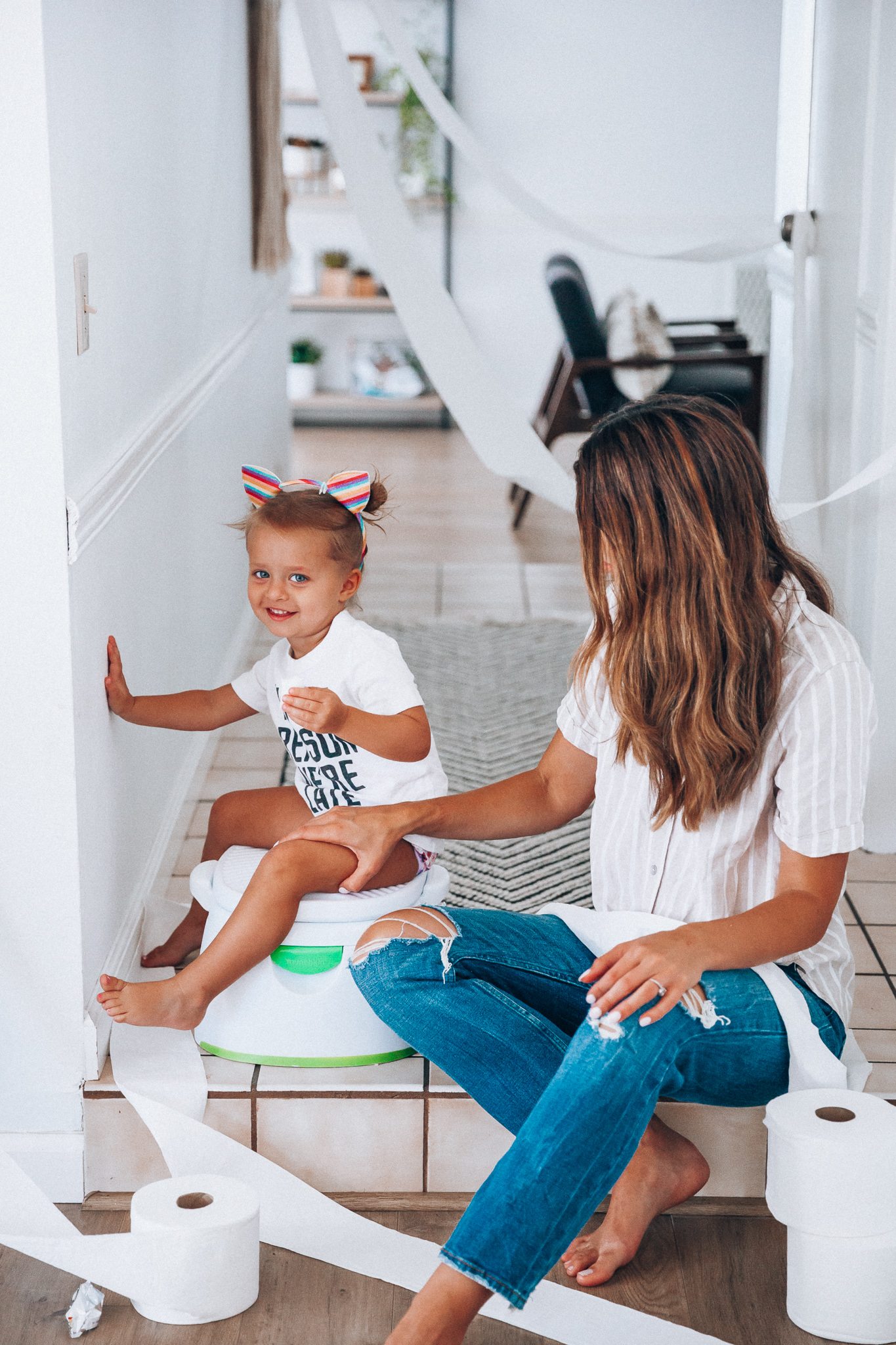 Our Potty Training Tips + Journey by popular San Francisco lifestyle blog, The Girl in the Yellow Dress: image of a woman and her daughter sitting on the ground with some toilet paper and a potty training toilet.