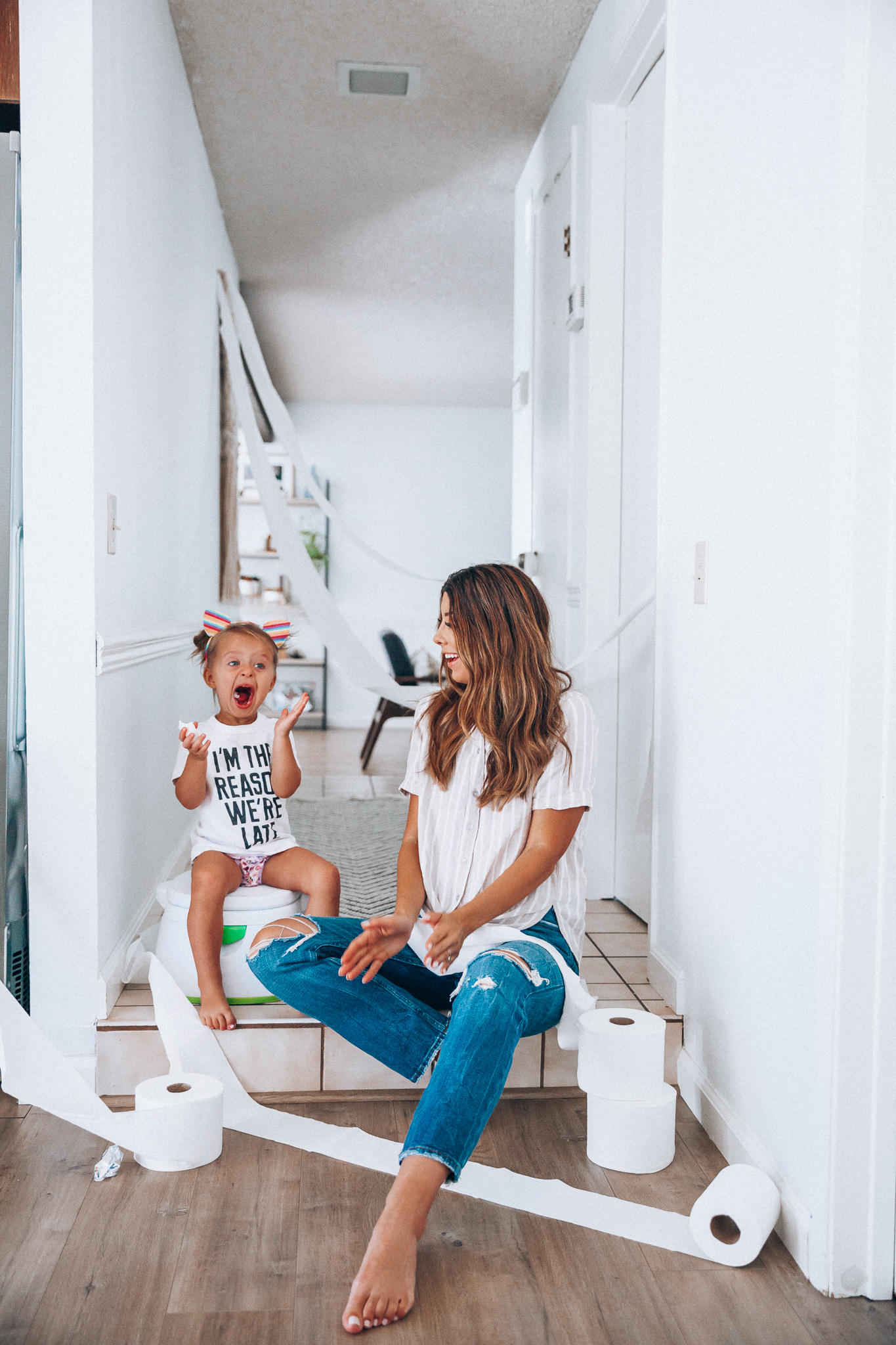 Our Potty Training Tips + Journey by popular San Francisco lifestyle blog, The Girl in the Yellow Dress: image of a woman and her daughter sitting on the ground with some toilet paper and a potty training toilet.