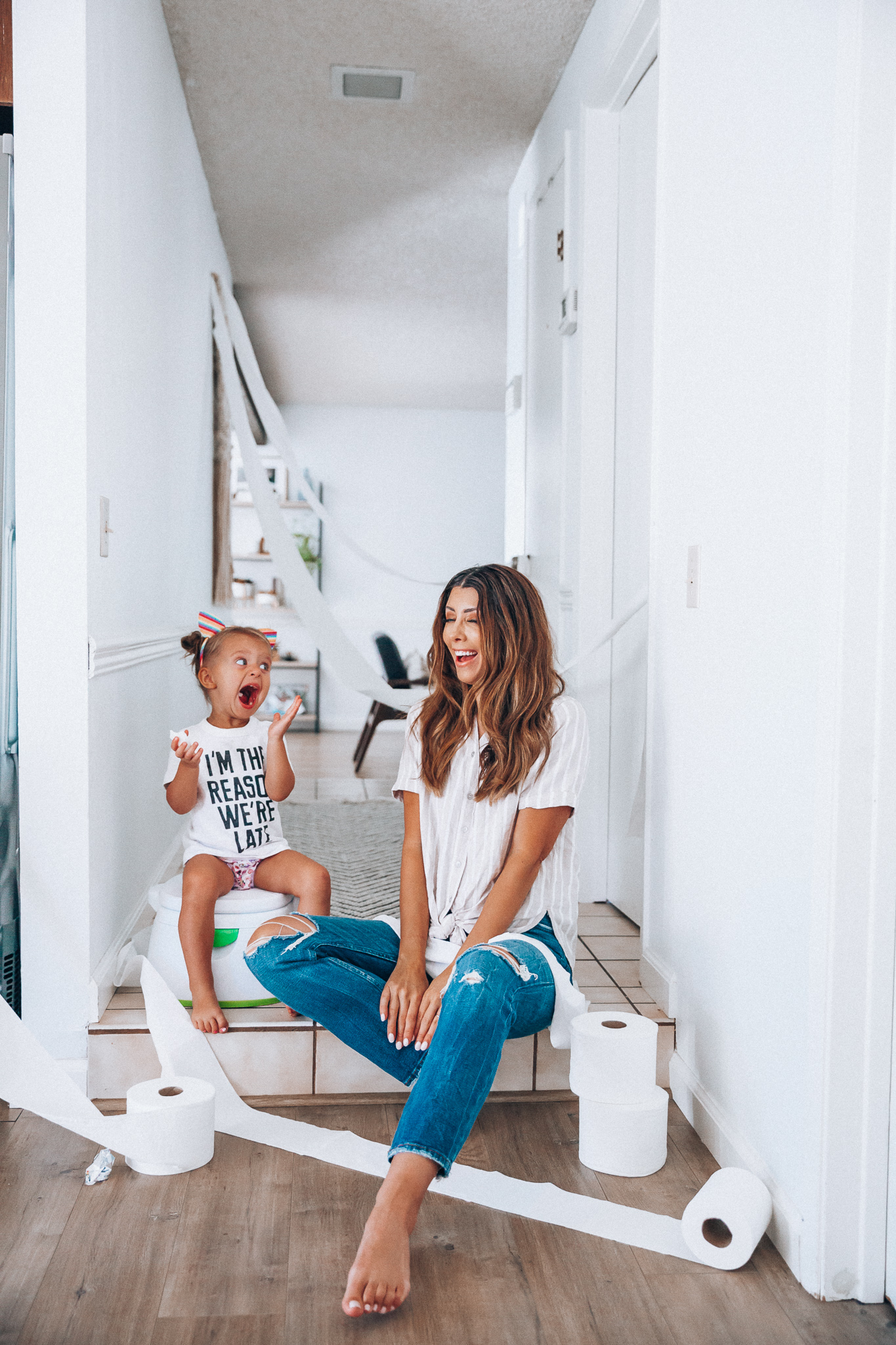 Our Potty Training Tips + Journey by popular San Francisco lifestyle blog, The Girl in the Yellow Dress: image of a woman and her daughter sitting on the ground with some toilet paper and a potty training toilet.