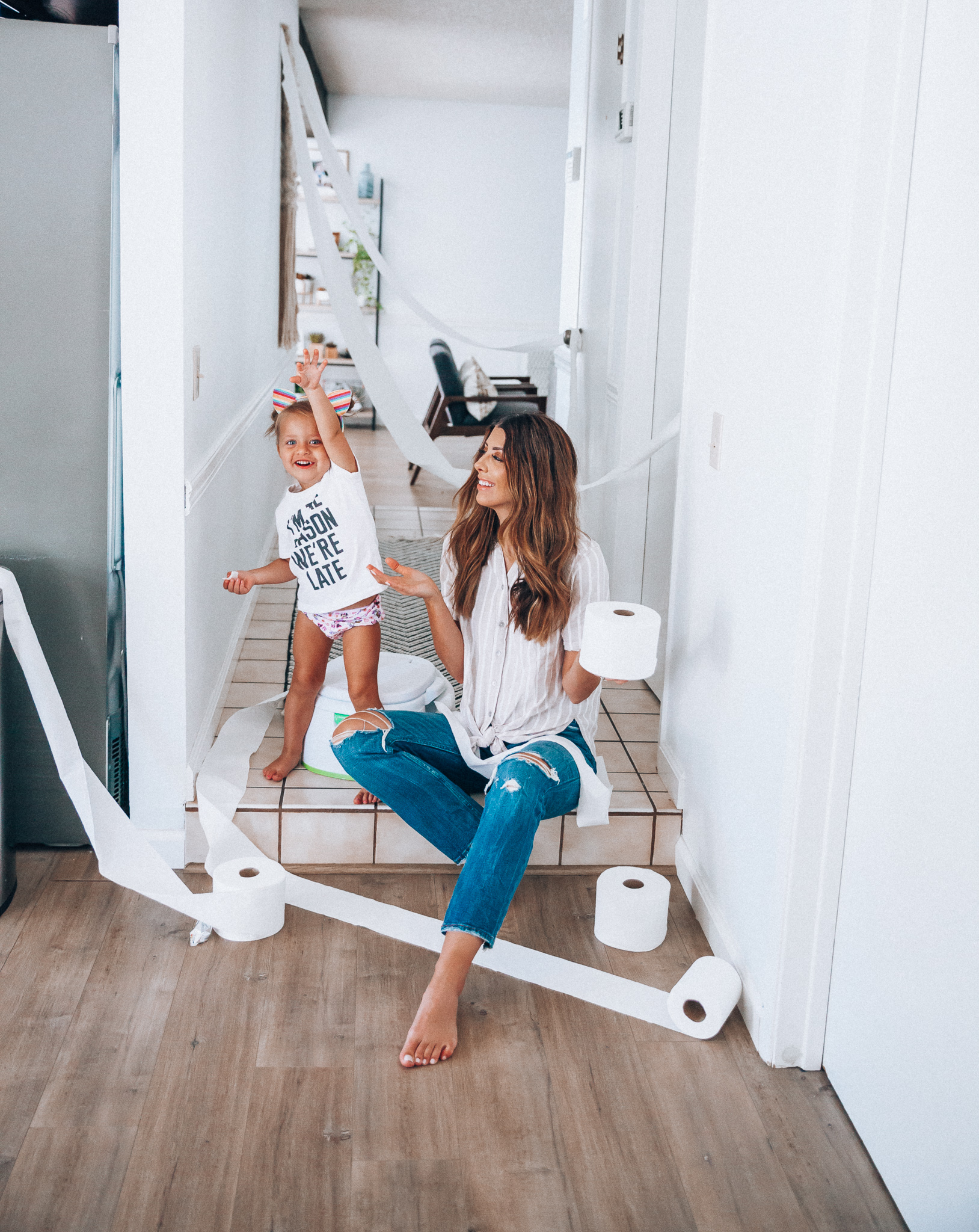 Our Potty Training Tips + Journey by popular San Francisco lifestyle blog, The Girl in the Yellow Dress: image of a woman and her daughter sitting on the ground with some toilet paper and a potty training toilet.