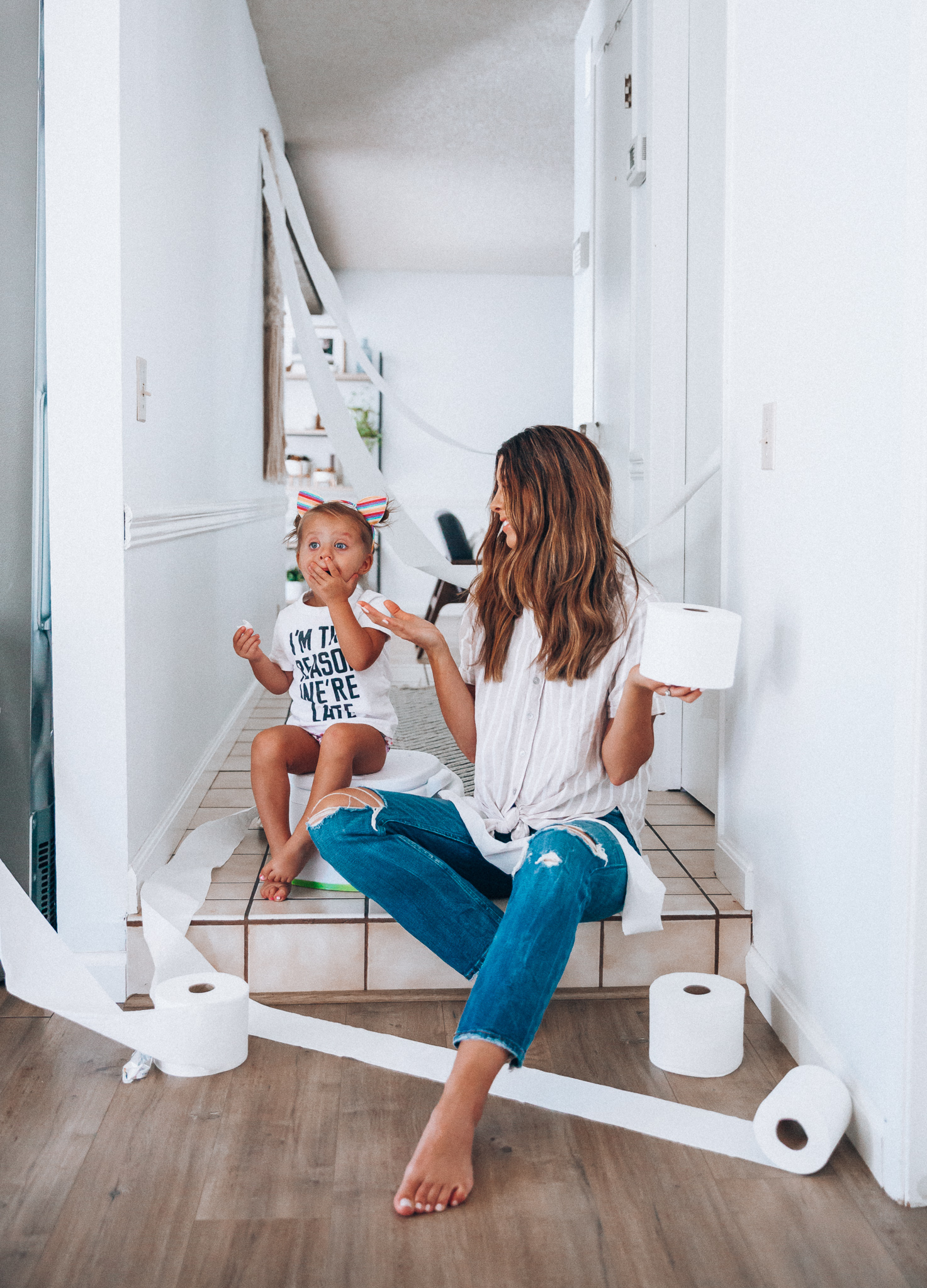 Our Potty Training Tips + Journey by popular San Francisco lifestyle blog, The Girl in the Yellow Dress: image of a woman and her daughter sitting on the ground with some toilet paper and a potty training toilet.